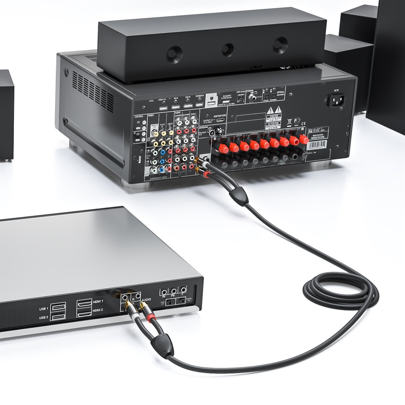 Schwarze Kabel verbinden einen DVD-Player mit einem Receiver und Lautsprechern. Weißer Hintergrund.