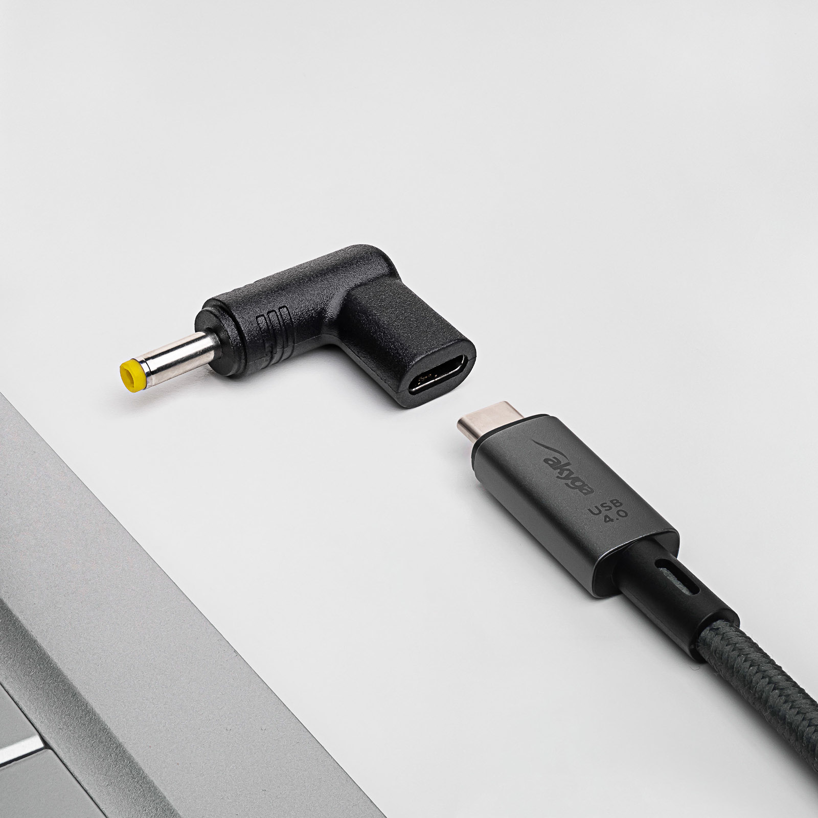 Un cavo USB-C nero e un adattatore nero a L con connettore CC, su una scrivania.