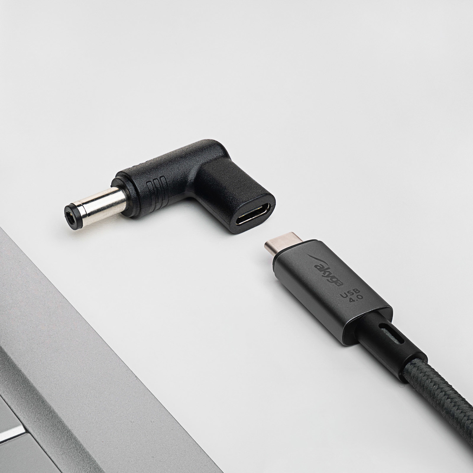 Adattatore angolato nero e grigio e cavo USB-C. Su una superficie bianca.