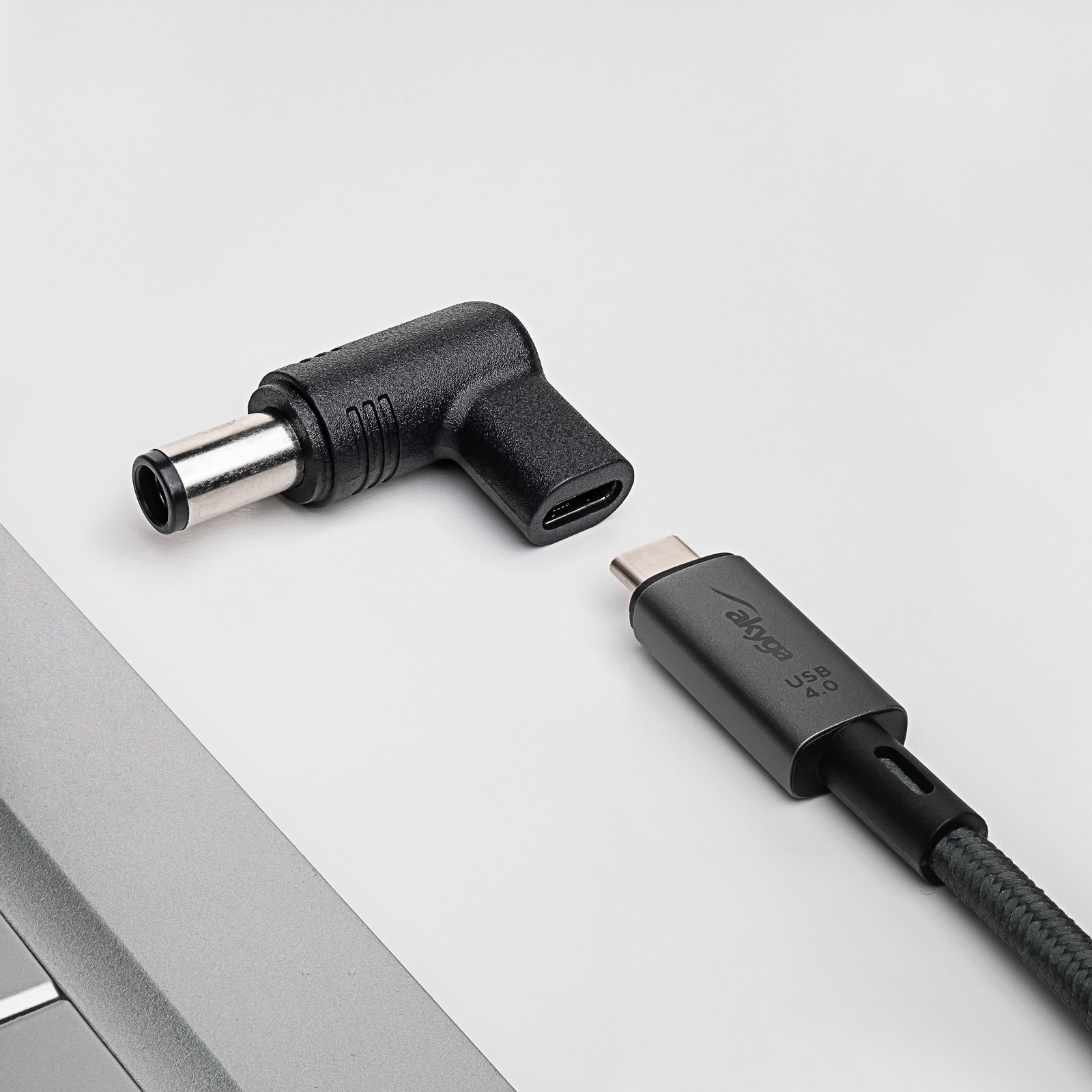 Adattatore angolato nero e grigio e cavo USB-C. Su una superficie bianca.