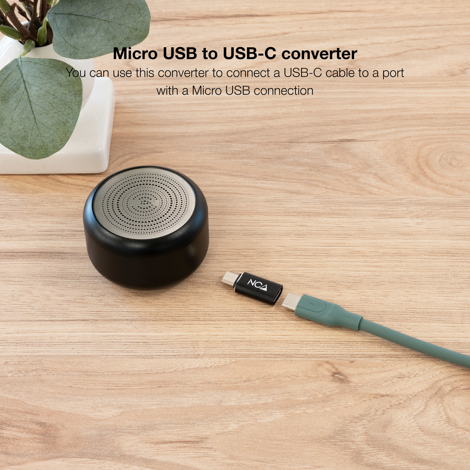 Un altoparlante nero e grigio con un cavo verde collegato a un adattatore Micro USB a USB-C nero.