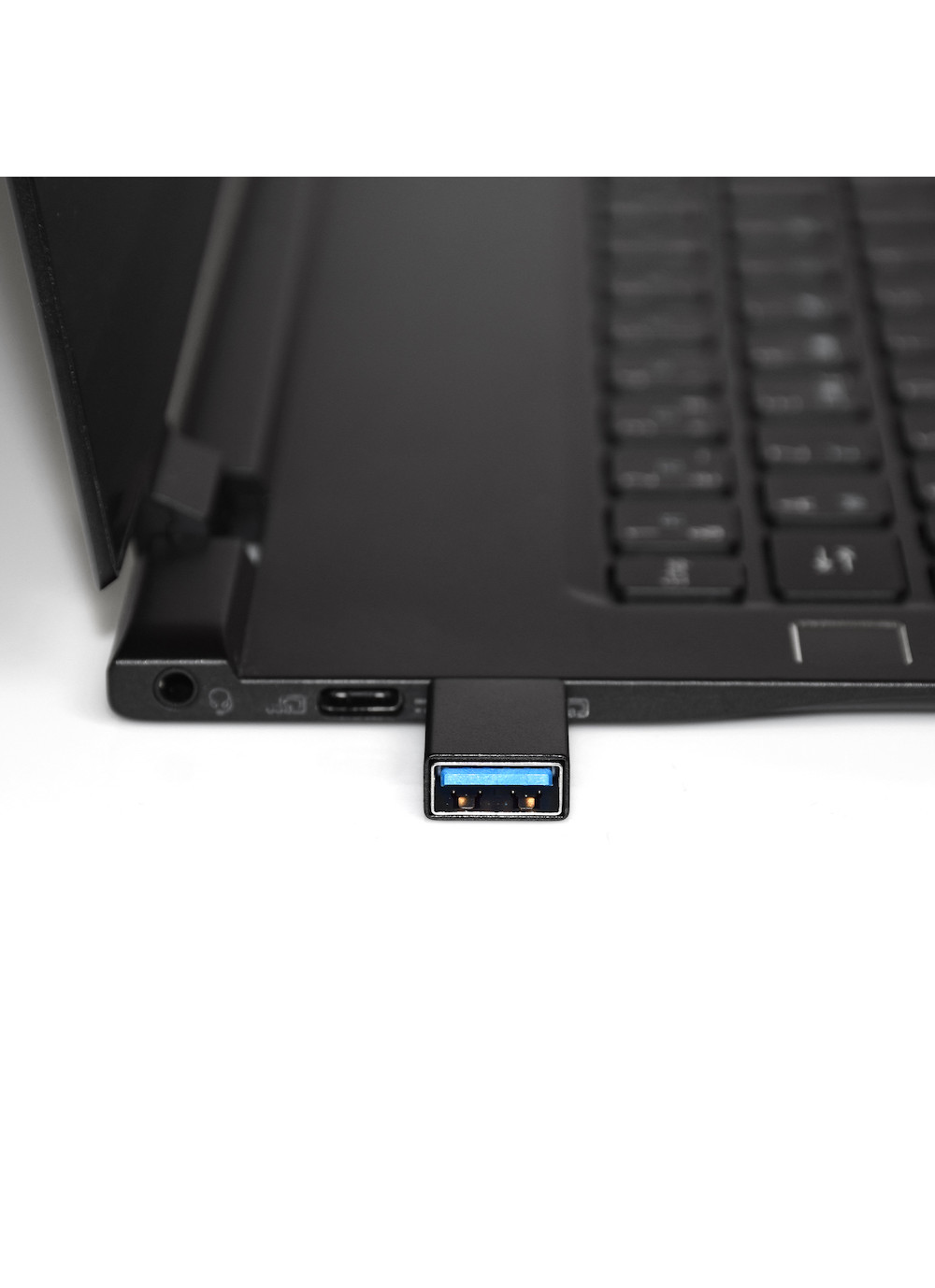 Laptop nero con adattatore USB collegato. Adattatore nero con porta blu.