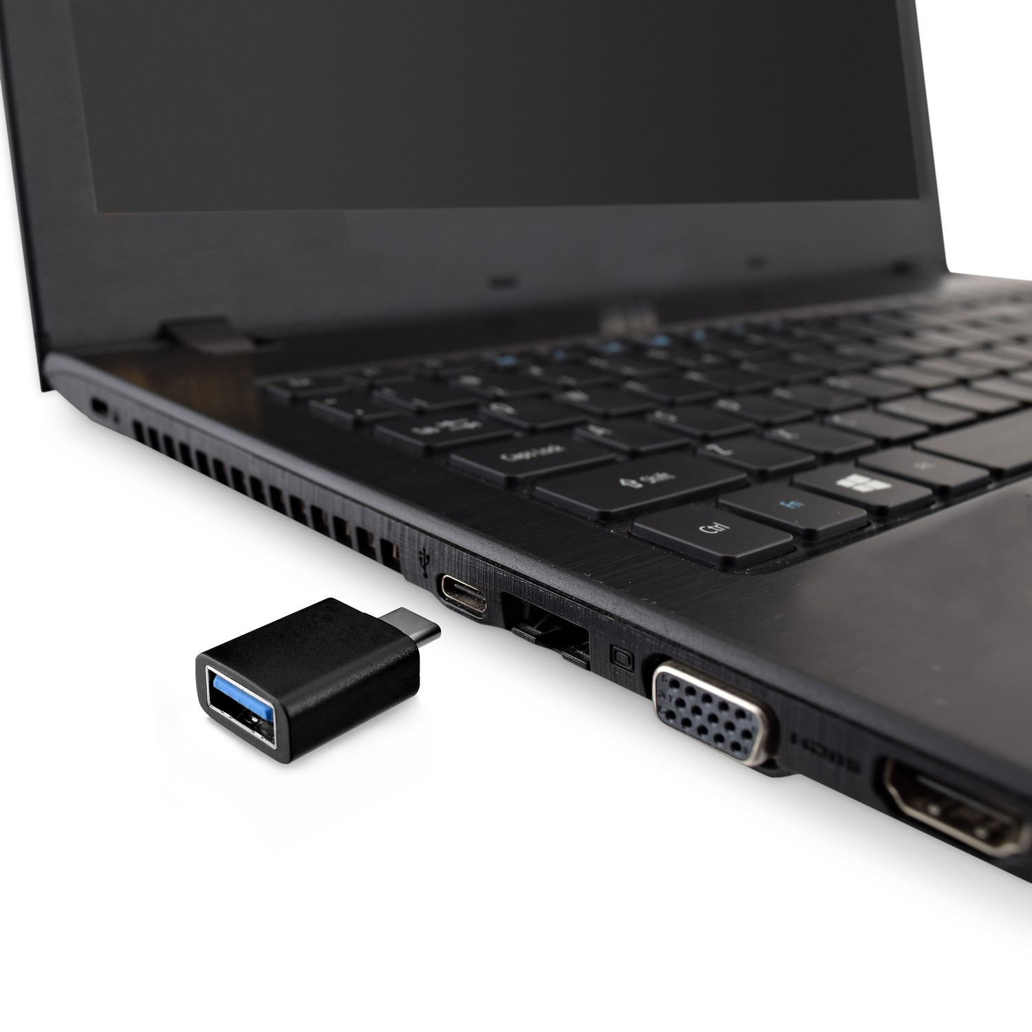 Een zwarte USB-A naar USB-C adapter aangesloten op een laptop. De laptop is zwart, op een wit oppervlak.