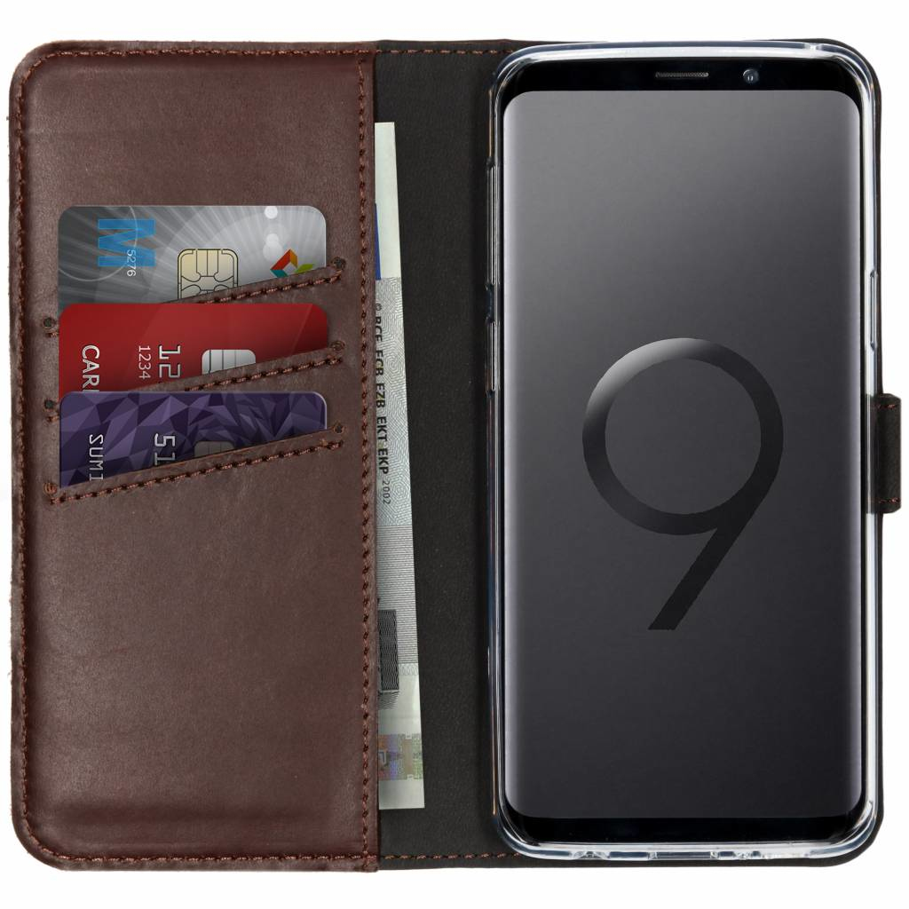 Bruine leren telefoonhoes met creditcards en telefoon erin.