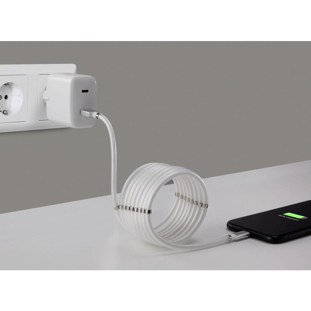 Biały zasilacz podłączony do gniazdka. Biały kabel zwinięty. Telefon się ładuje.