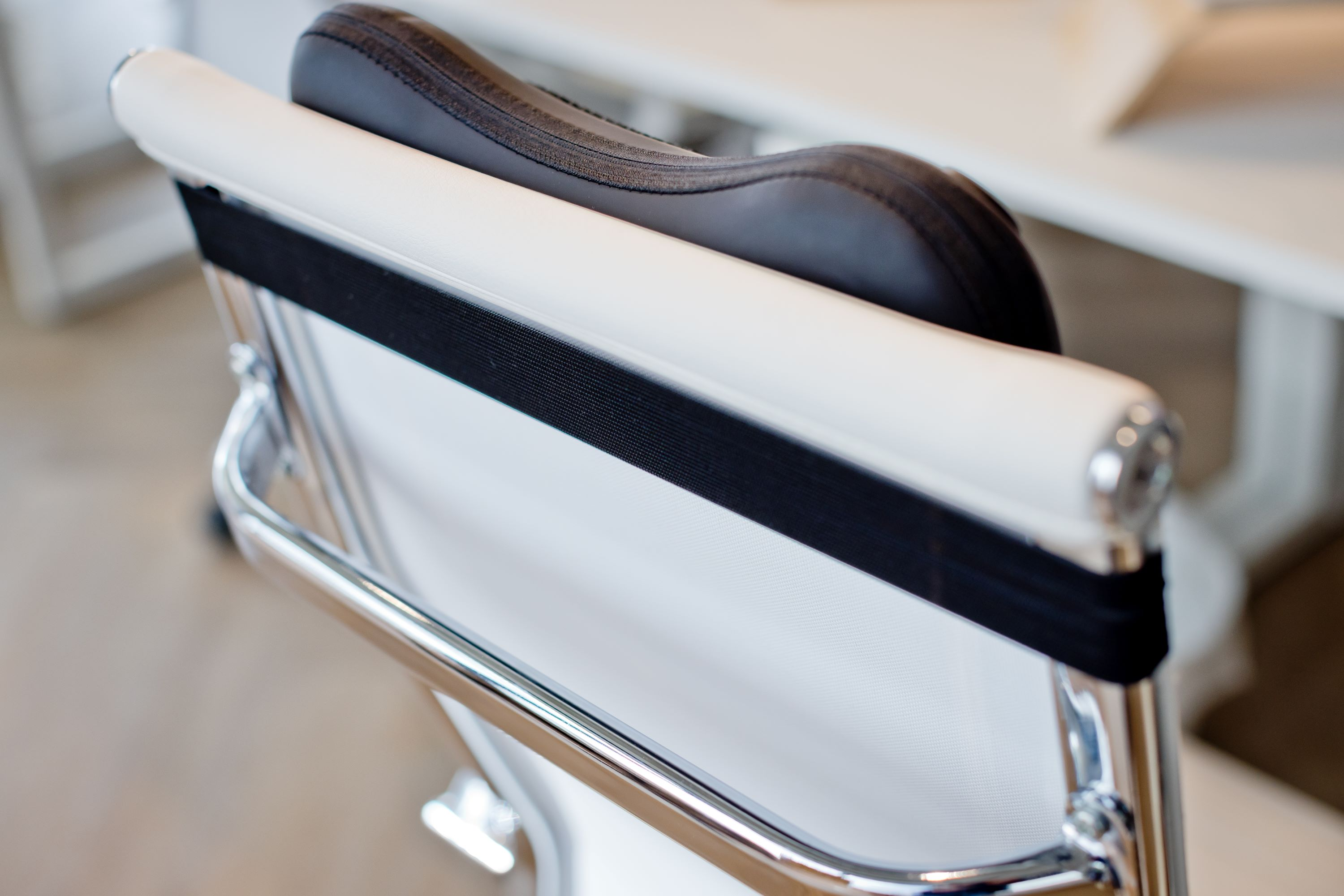 A close-up of a white office chair. The chair's back is white and the seat is black.