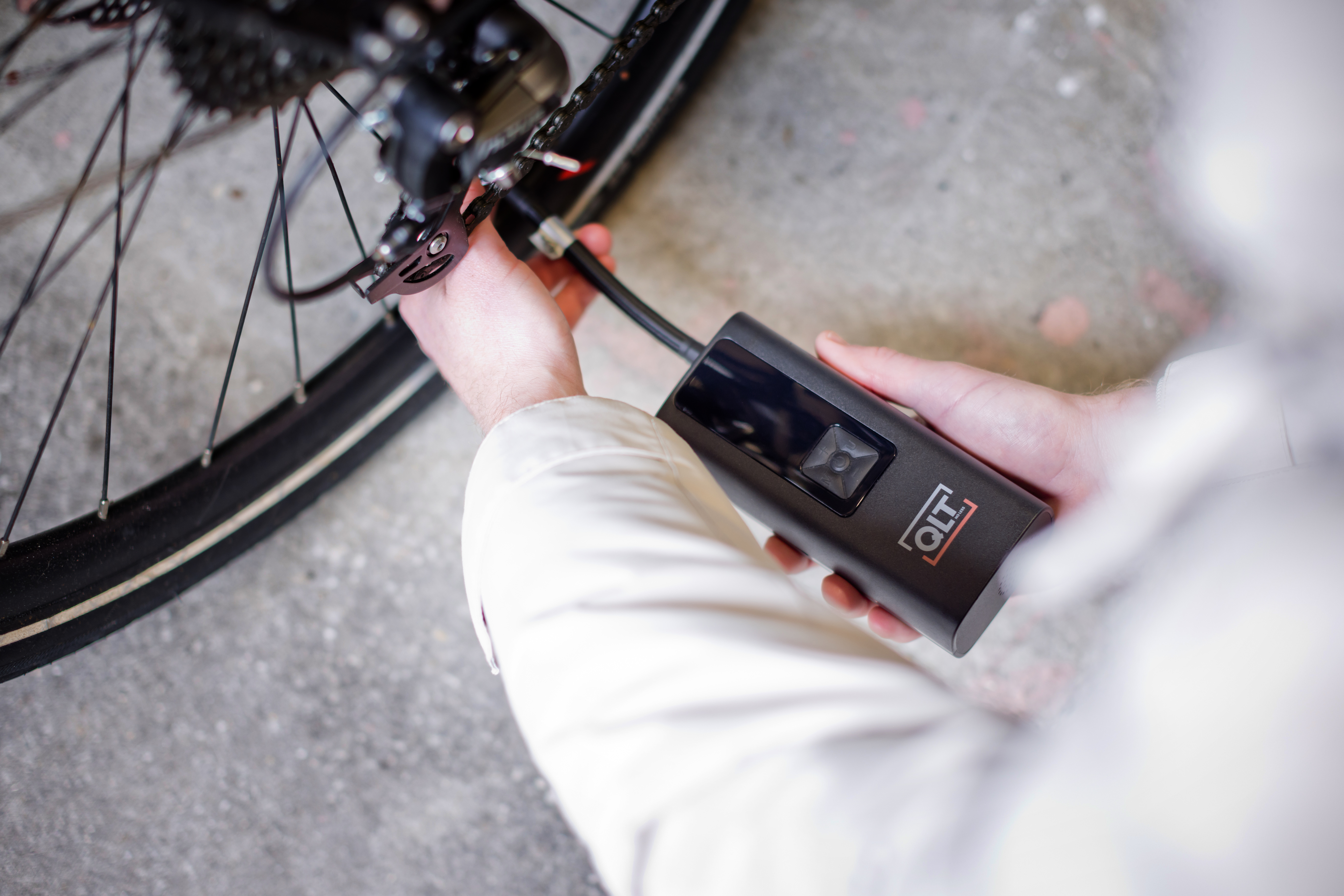Person pumping a bicycle tire using a black QLT device.