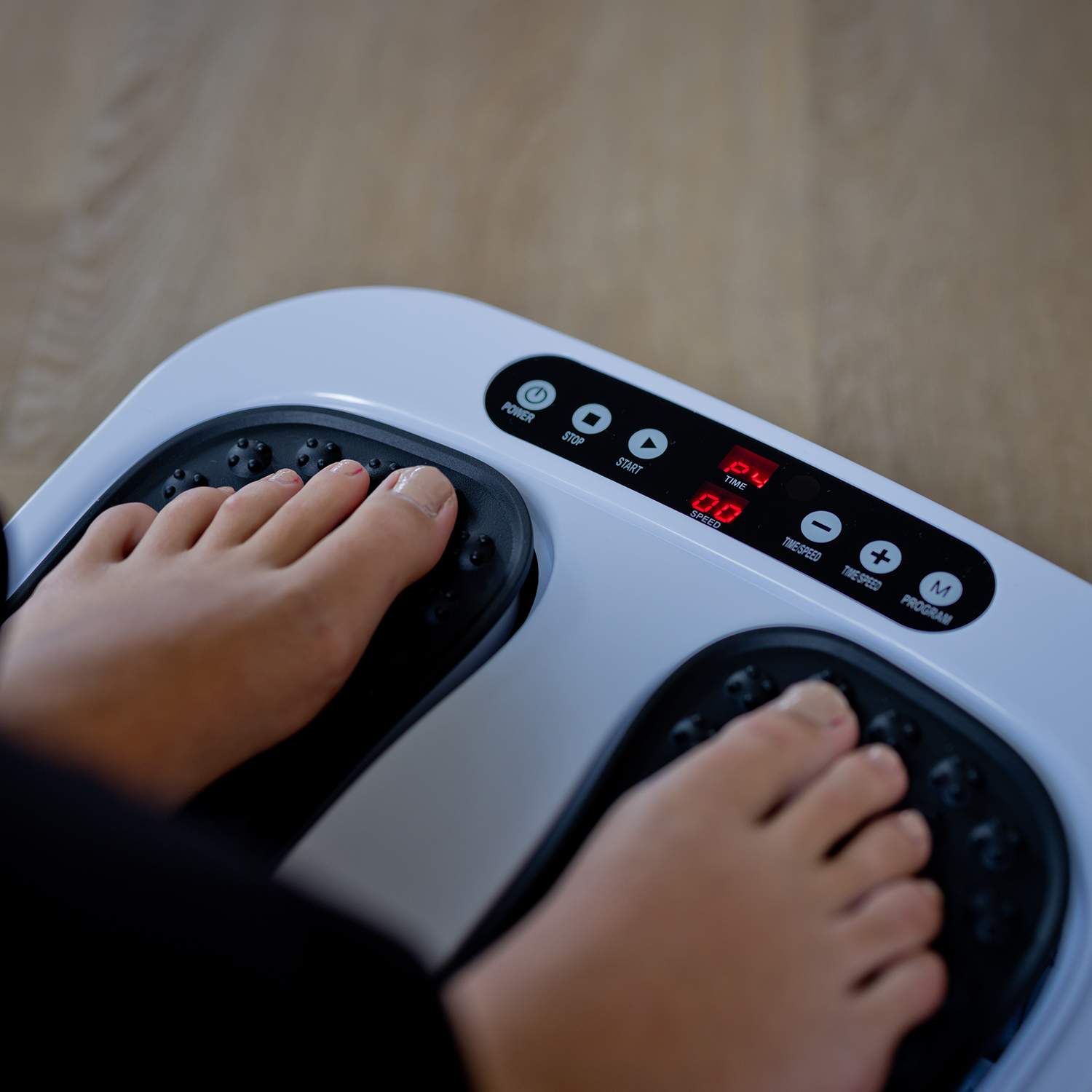 Feet on a foot massager. The feet are on the black massager pads, a display is visible.