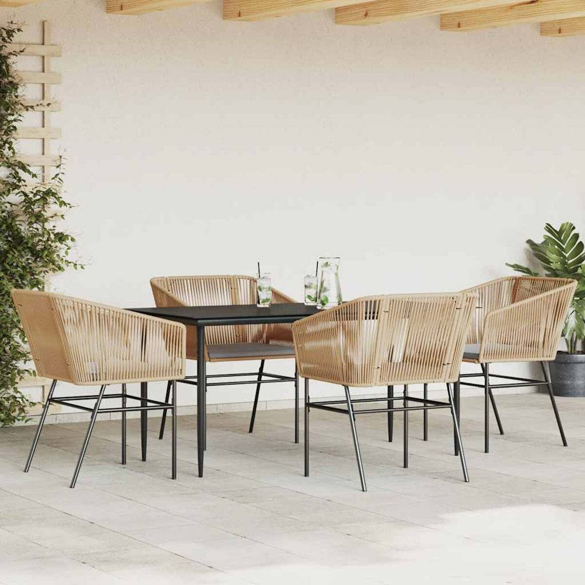 Set da pranzo all'aperto con tavolo nero, quattro sedie e sfondo parete bianca.