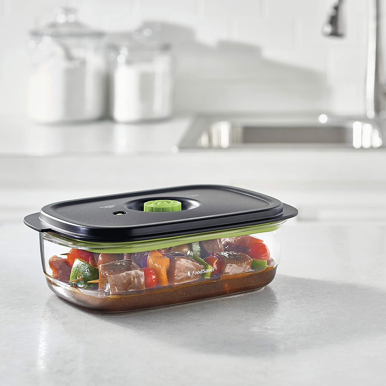 Contenitore per alimenti con cibo cotto in cucina, con piano di lavoro bianco.