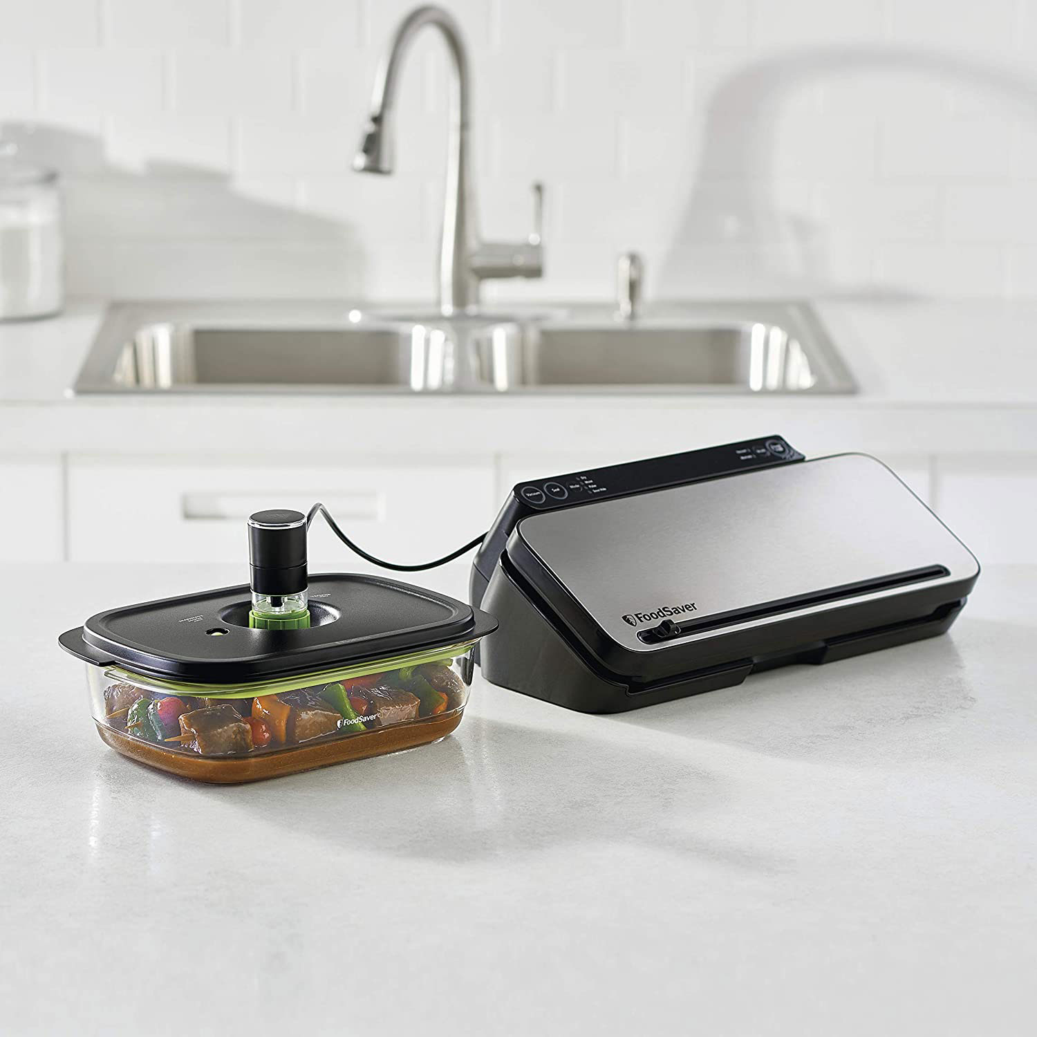 Ein Foodsaver-Vakuumiergerät mit einem Lebensmittelbehälter. Im Hintergrund ist eine Küchenarbeitsplatte.