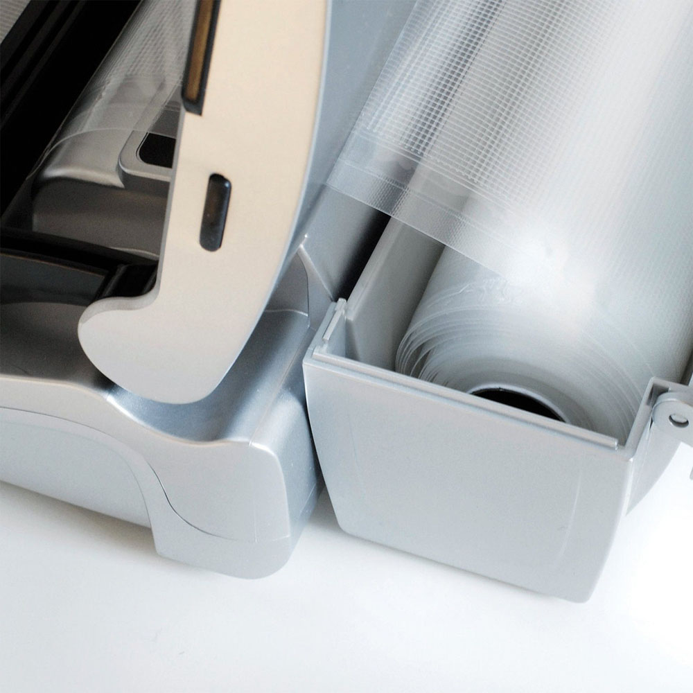 Sigillatrice sottovuoto con rotolo di plastica trasparente all'interno. Grigio e bianco. Sfondo bianco.