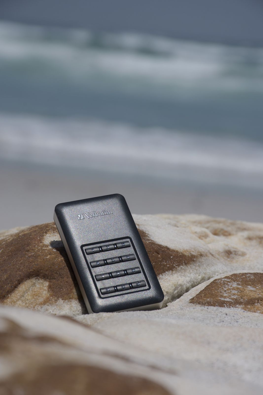Czarne i szare urządzenie do przechowywania danych na skale. Tło to ocean i plaża.