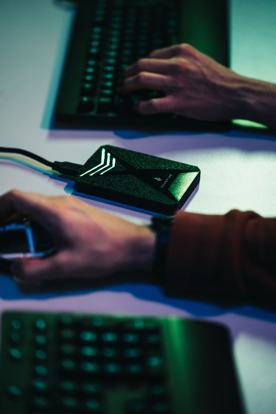 Ręce używają laptopa, czarnego zewnętrznego dysku twardego i myszy na białej powierzchni.