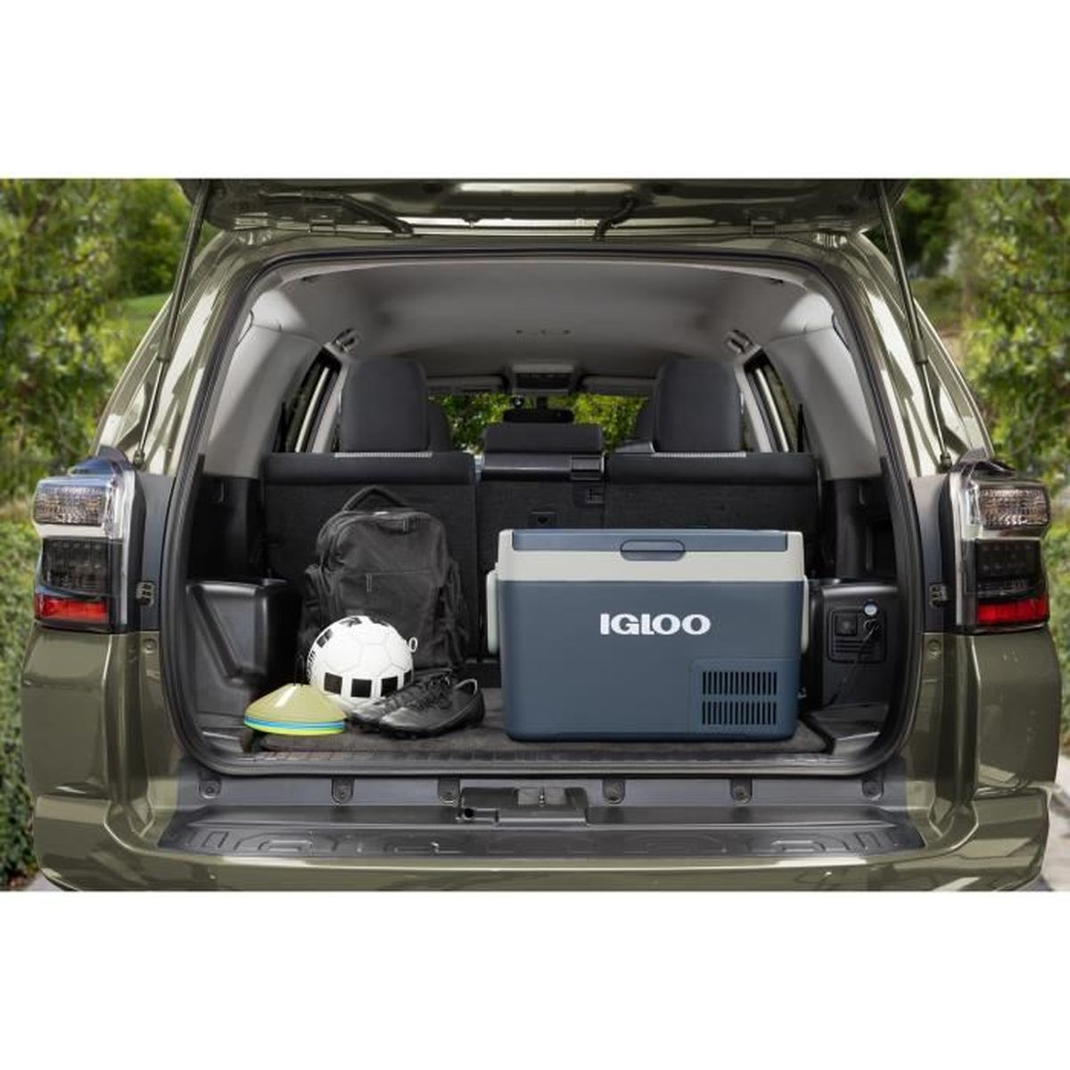 Bagażnik SUV z chłodziarką, sprzętem sportowym i czarnym plecakiem.