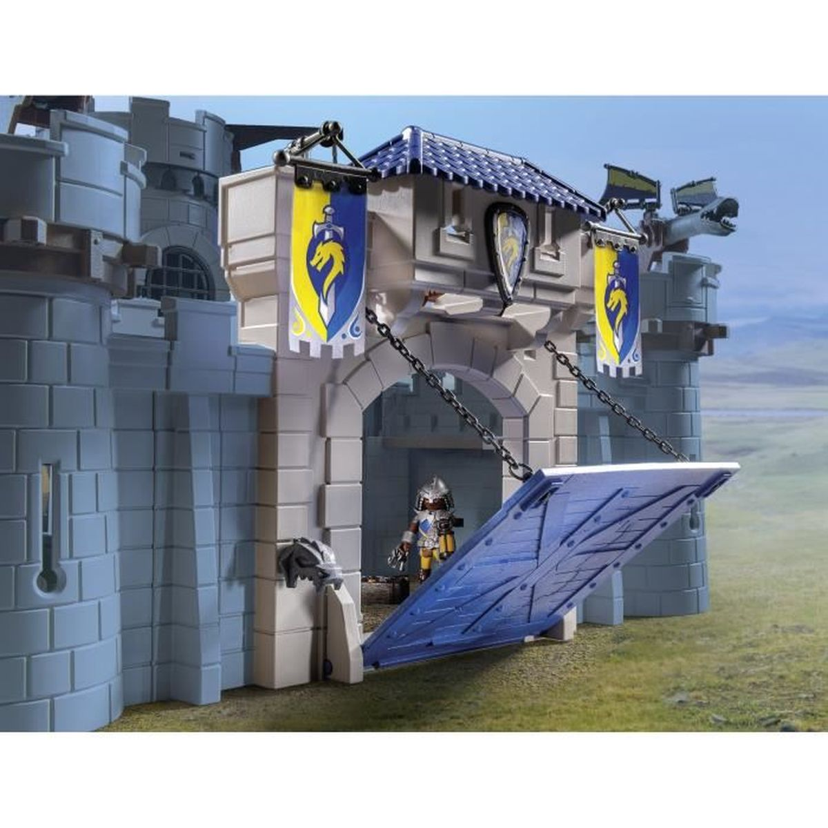 Un castello giocattolo con un ponte levatoio abbassato. Un cavaliere è vicino al ponte. Bandiere e stendardi visibili.