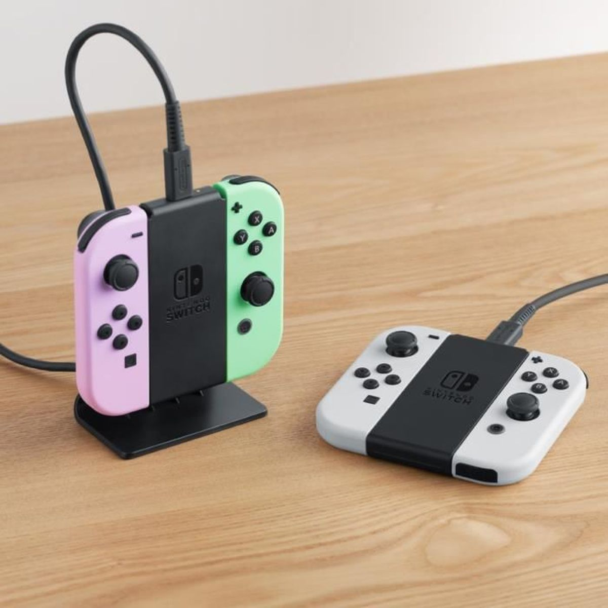 Due controller Nintendo Switch e una base di ricarica. Uno è rosa e l'altro verde.