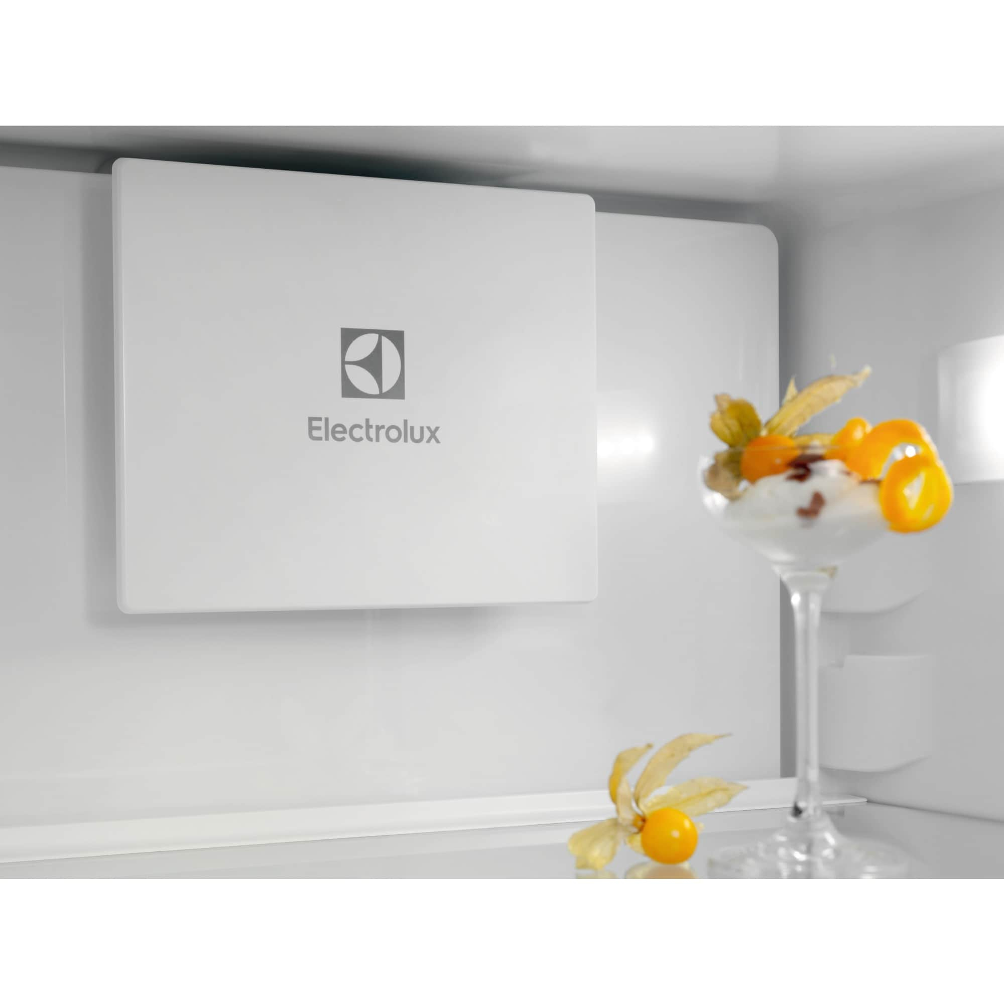 All'interno di un frigorifero in acciaio inossidabile, un pannello bianco con il logo Electrolux e un dessert in un bicchiere.