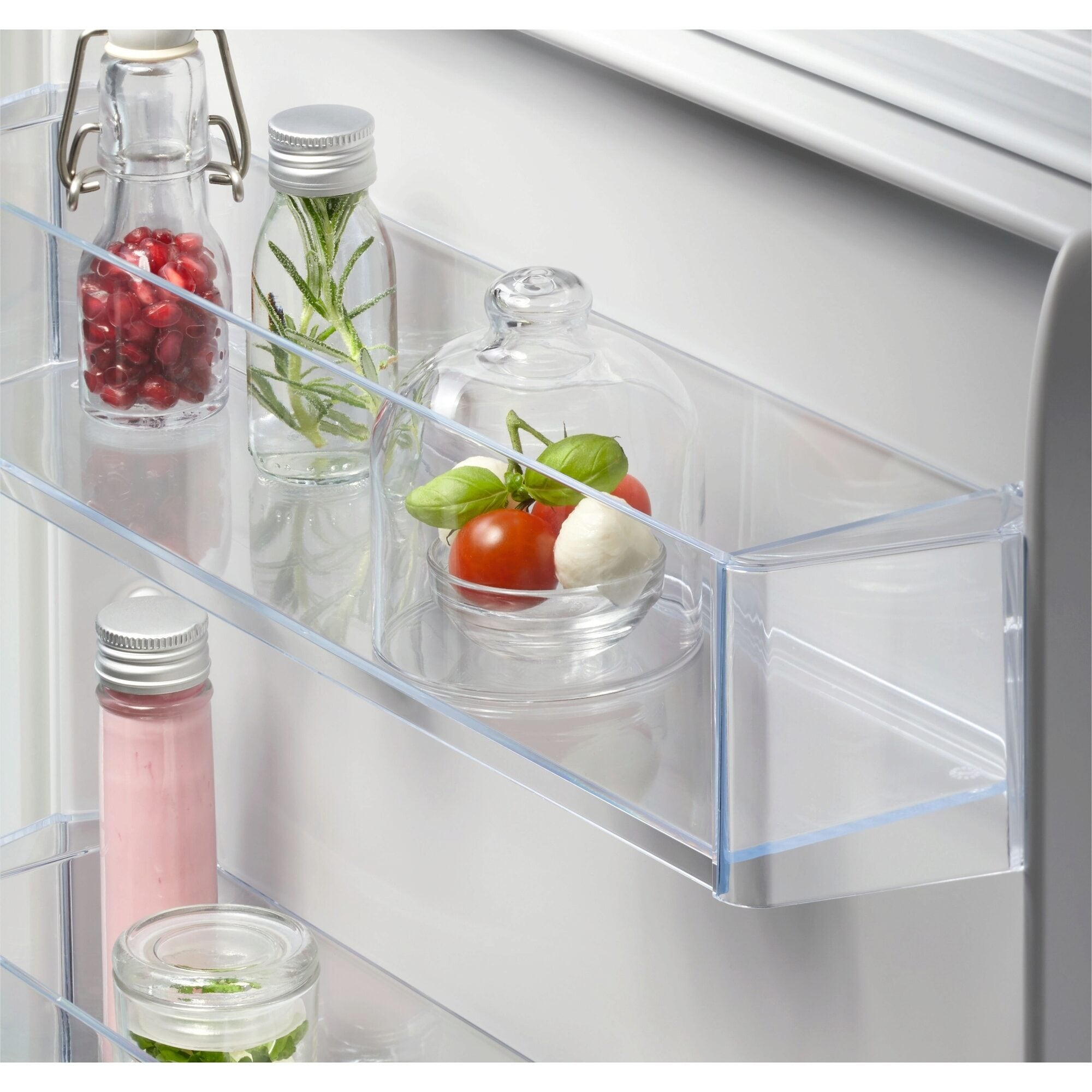 Estantes de frigorífico con frascos de vidrio que contienen alimentos. Los frascos contienen líquidos y comida.