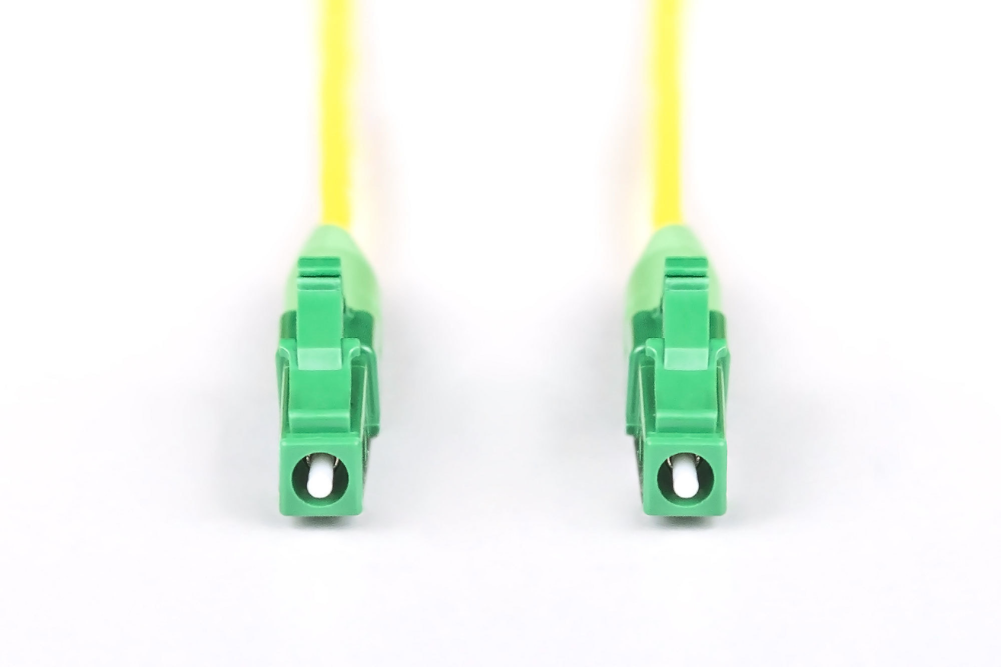 Zwei grüne Stecker, die an gelben Kabeln befestigt sind, werden auf weißem Hintergrund präsentiert.
