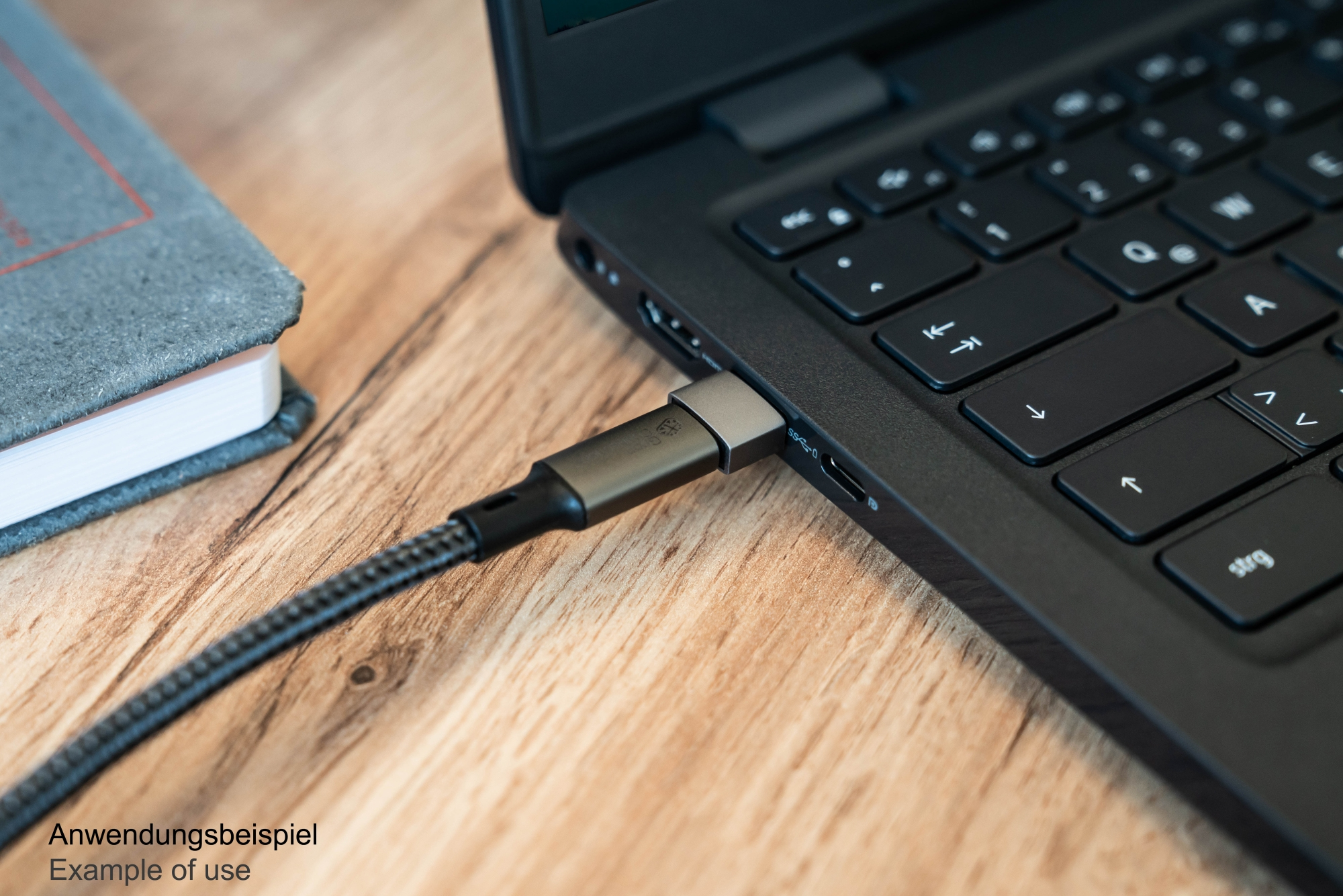 Cavo collegato a un laptop, con un taccuino sulla scrivania.