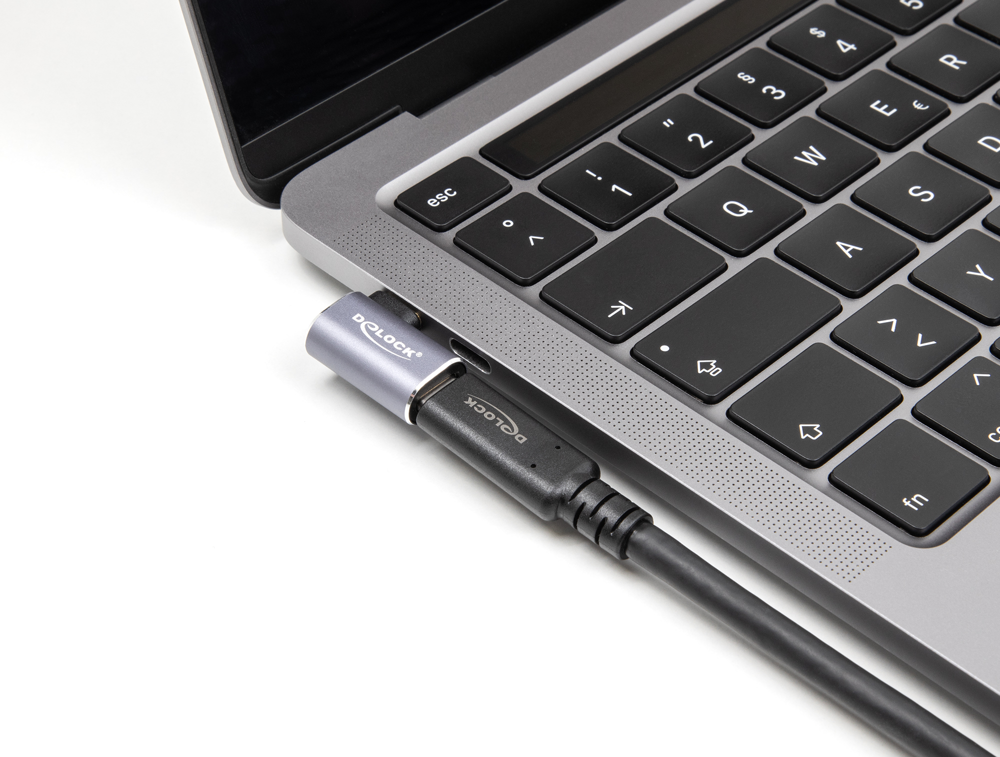 Un laptop grigio con tastiera nera e un cavo nero con connettore argentato collegato.