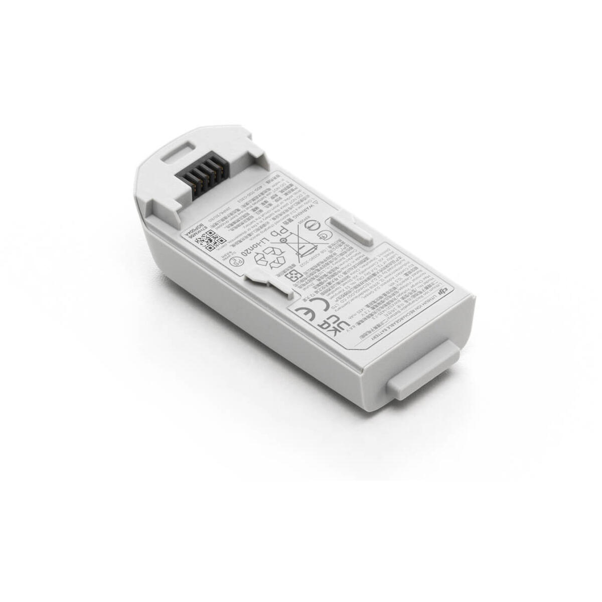 Una piccola batteria grigia con etichette, appoggiata su una superficie bianca.