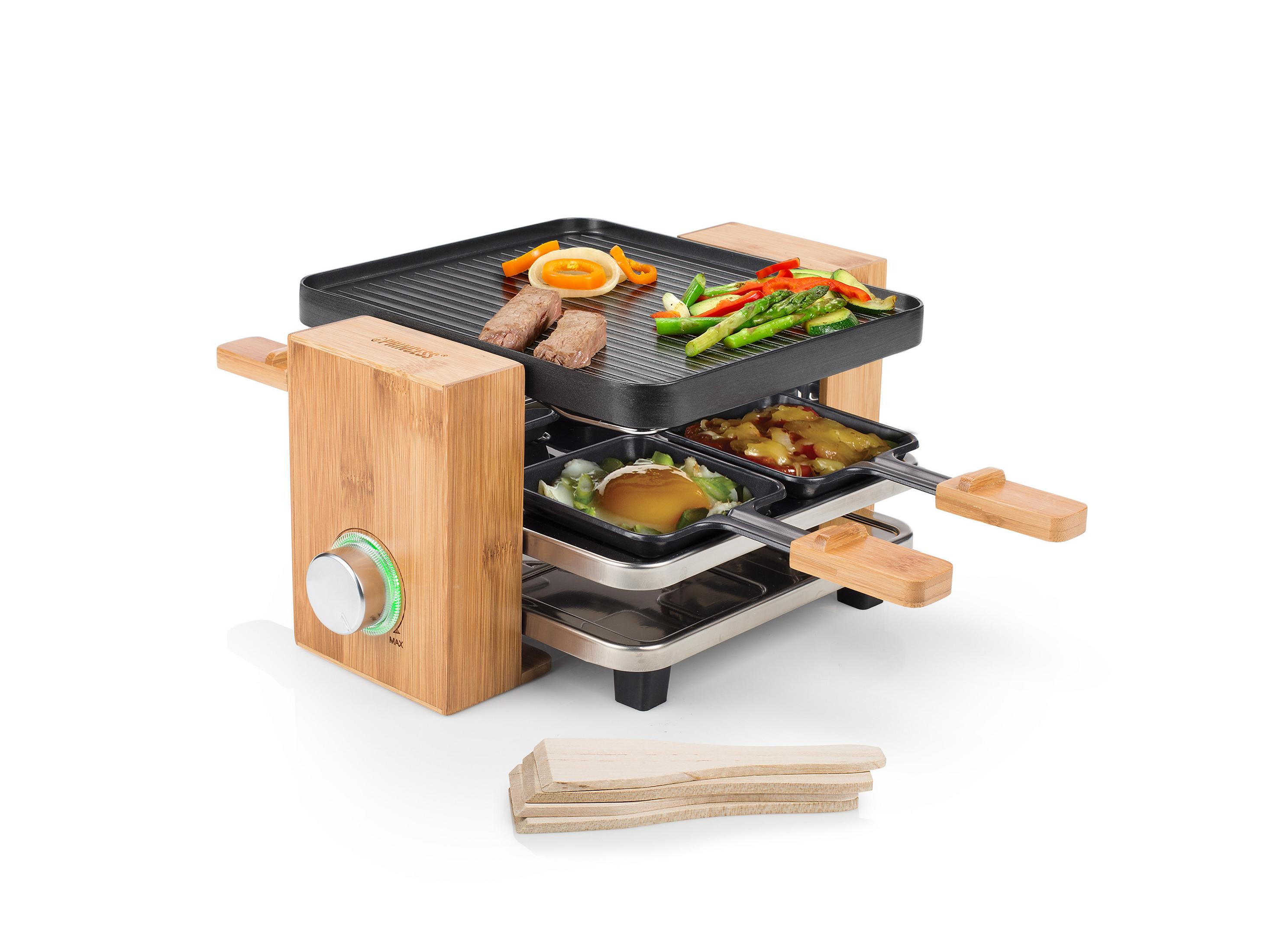 Griglia per raclette con cibo sopra. Pannelli laterali in legno, spatole in legno davanti.