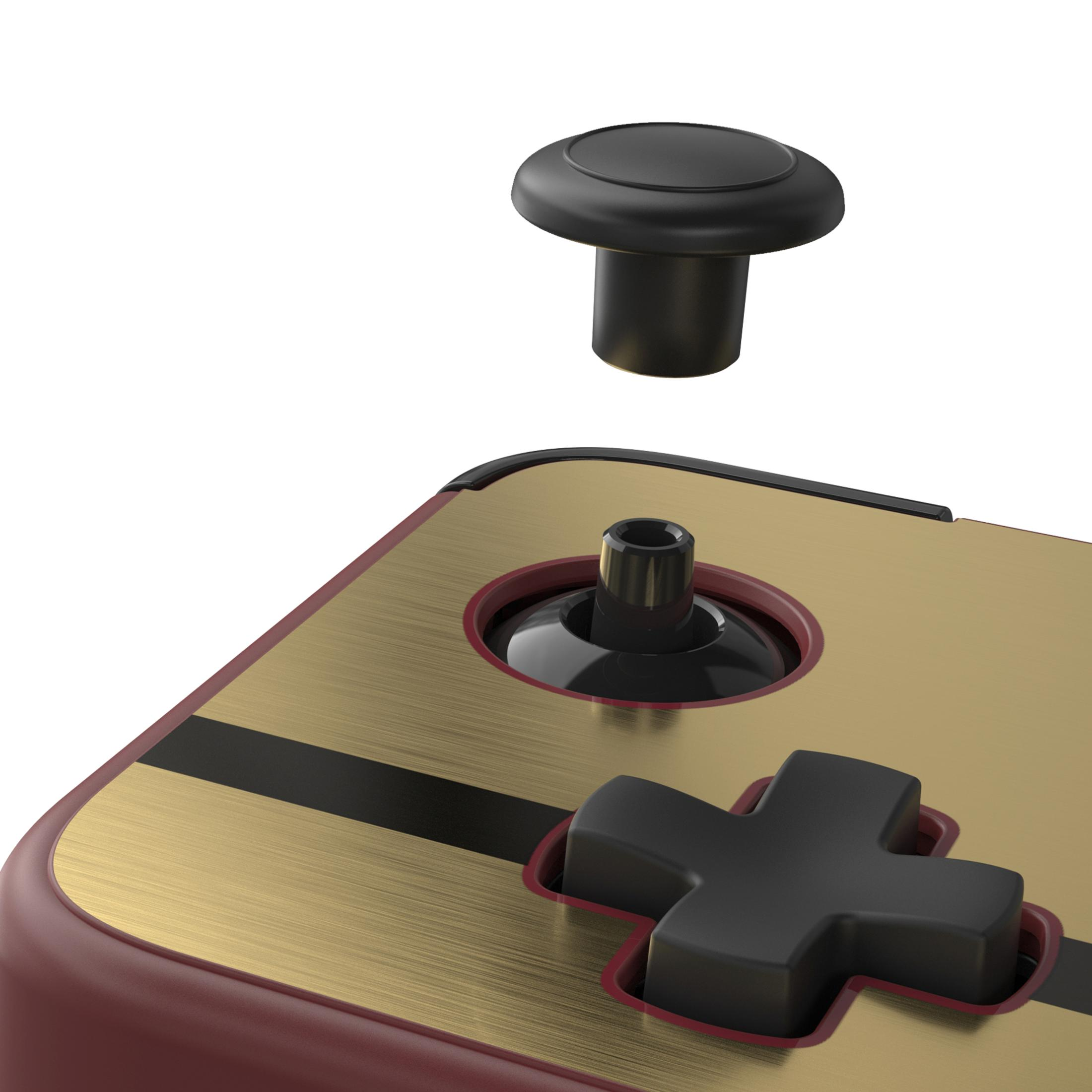 Primo piano della superficie dorata di un controller, pulsante a croce nero e joystick staccato.