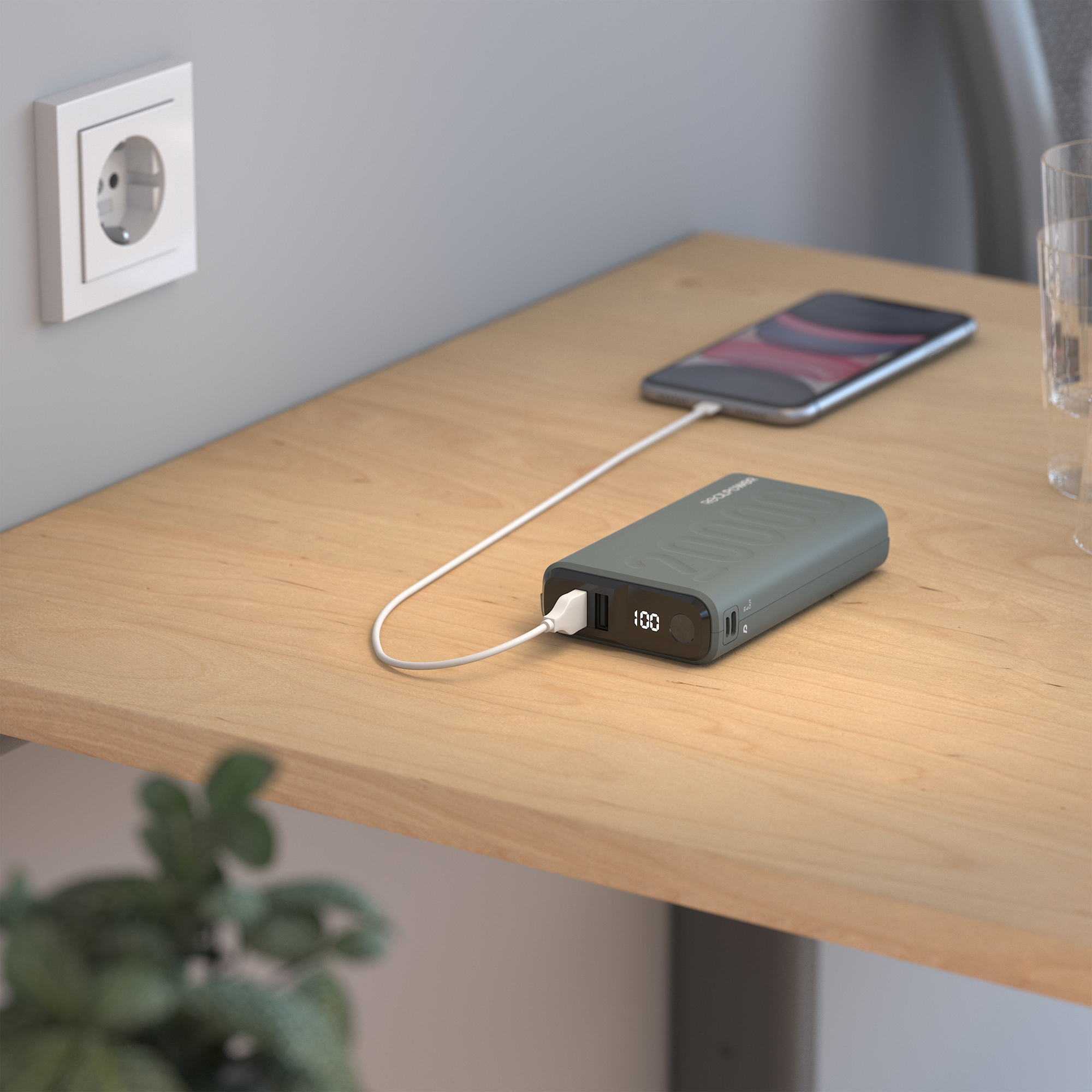 Ein Telefon, das auf einem Holztisch mit einer Powerbank geladen wird. Eine Steckdose ist links sichtbar.