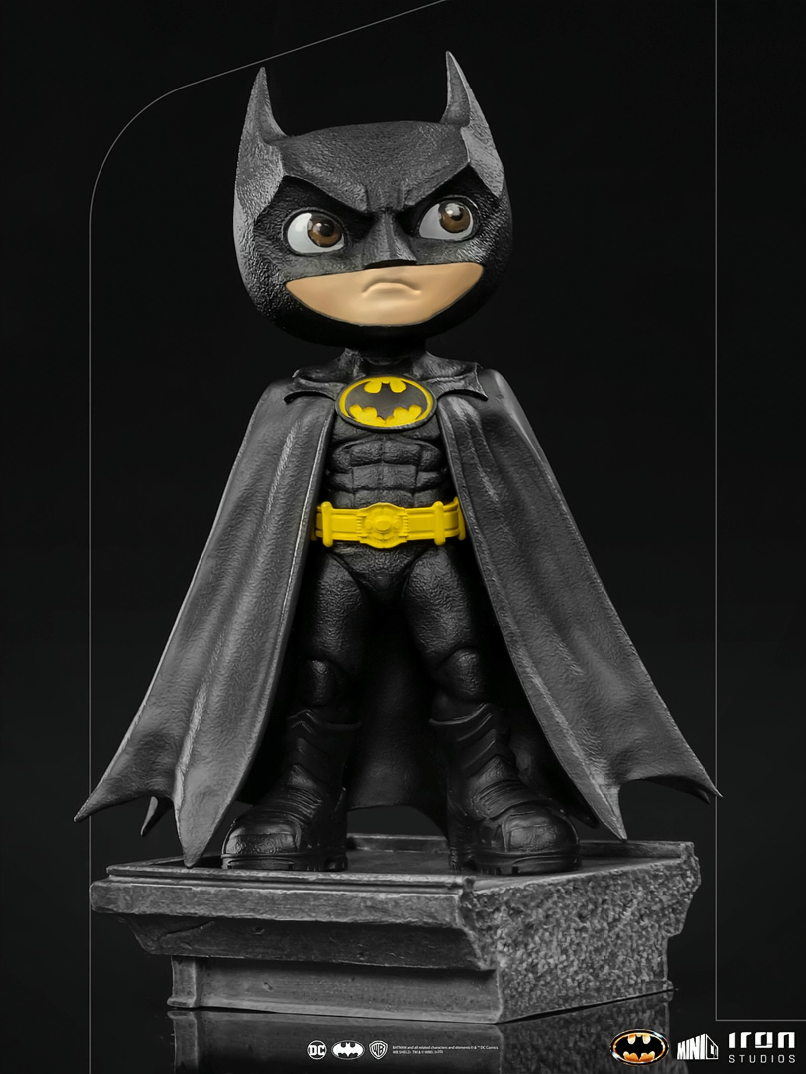 Eine Batman-Figur, die auf einem Sockel steht. Sie ist schwarz und hat einen gelben Gürtel.