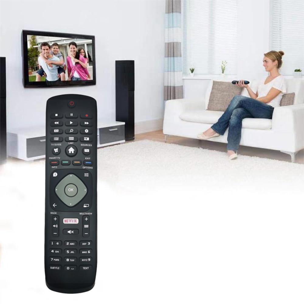 Schwarze Fernbedienung mit vielen Knöpfen, die auf einen Fernseher an der Wand zeigt.