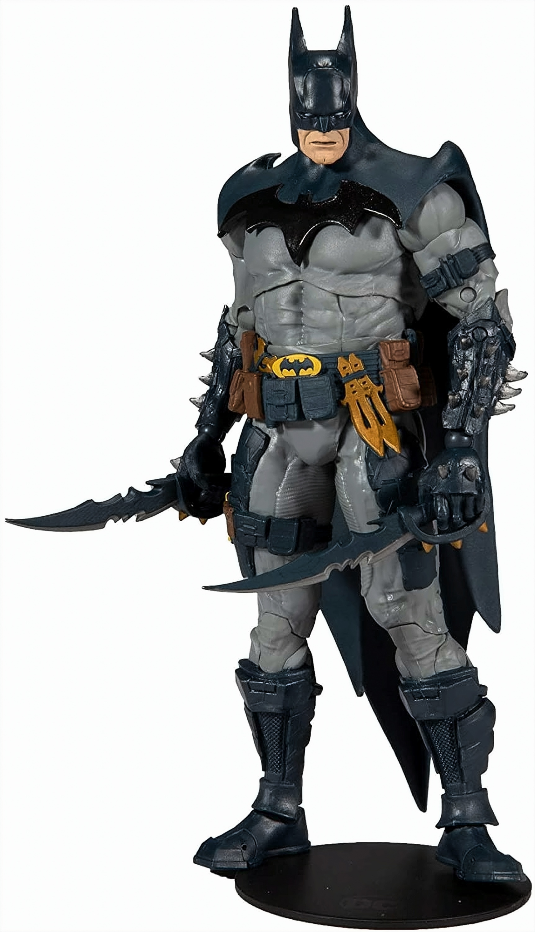 Batman-Actionfigur mit grauem und schwarzem Anzug, hält zwei Klingen. Steht auf schwarzer Basis.