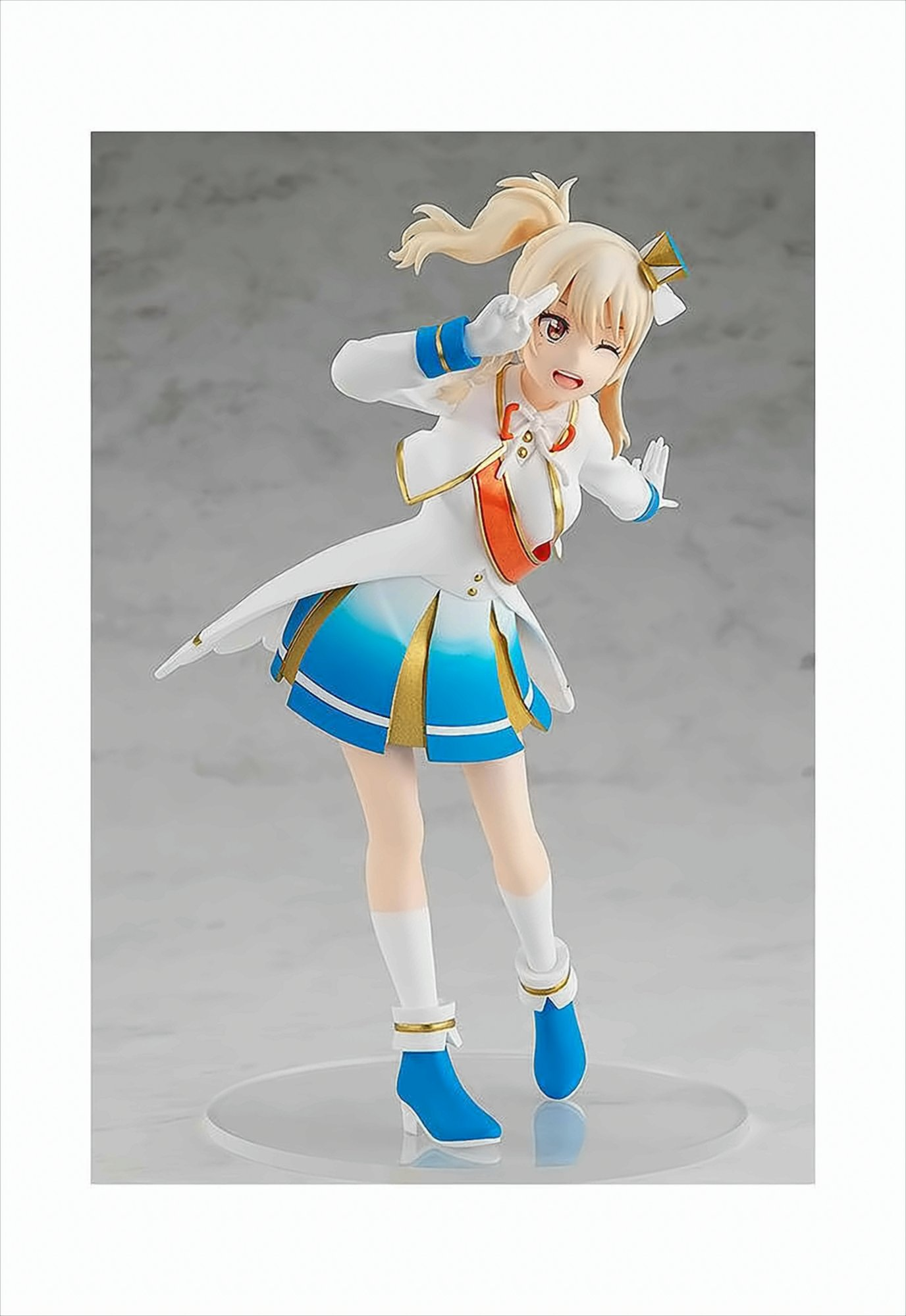 Anime-Figur in weiß-blauem Outfit, zwinkernd und winkend. Blondes Haar und klarer Sockel.
