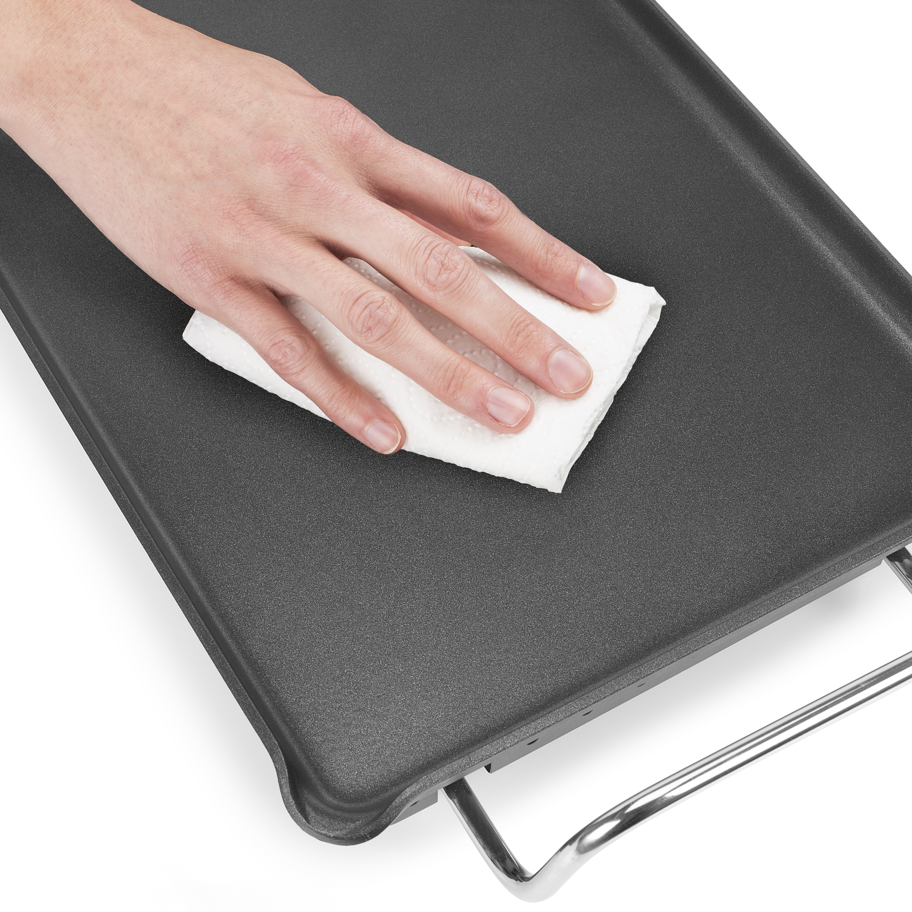 Ręka wycierająca szarą płytę grzewczą białą serwetką, pokazująca powierzchnię płyty.