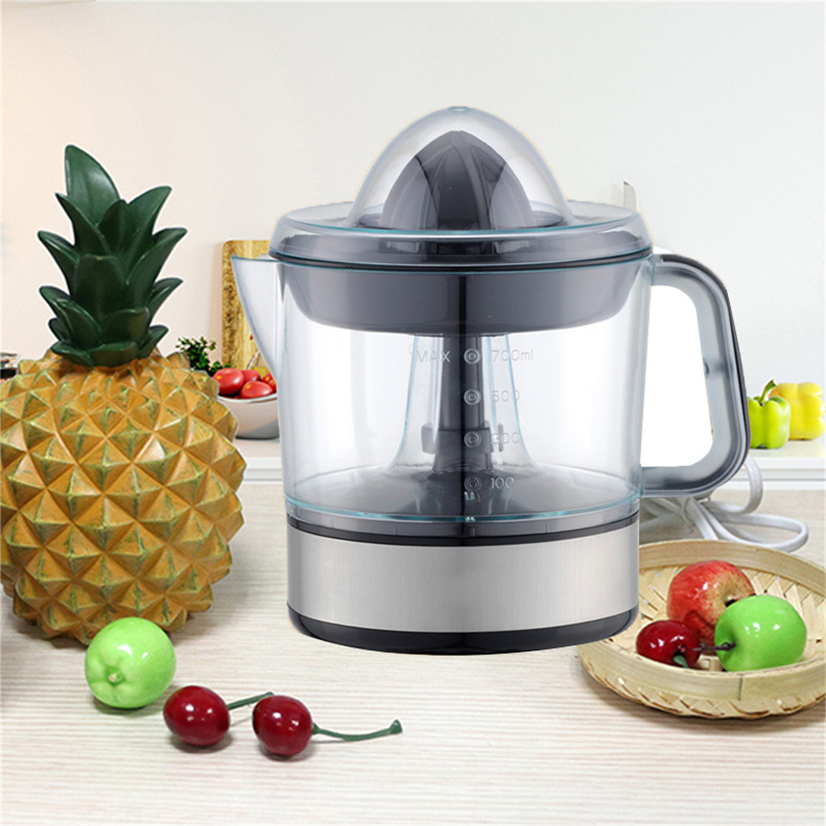 Ein silber-schwarzer Entsafter mit Ananas und Früchten auf einem Tisch.
