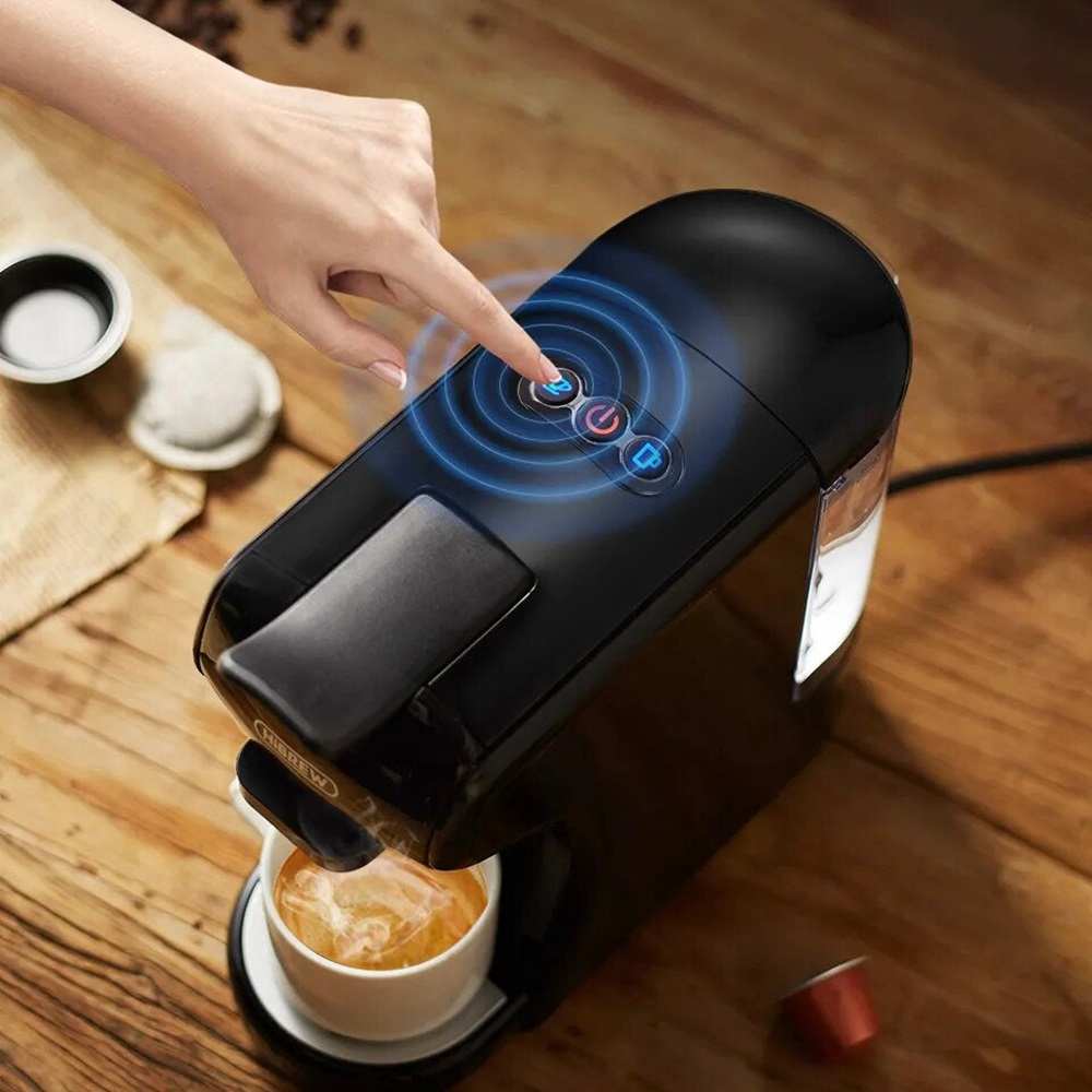Un dedo presionando un botón en una cafetera negra y plateada.