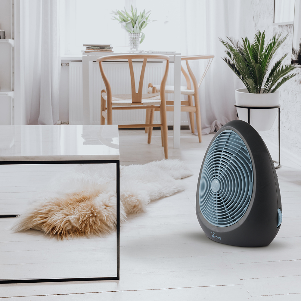 Ciemnoszary i niebieski grzejnik wentylatorowy w białym pokoju z meblami i roślinami.