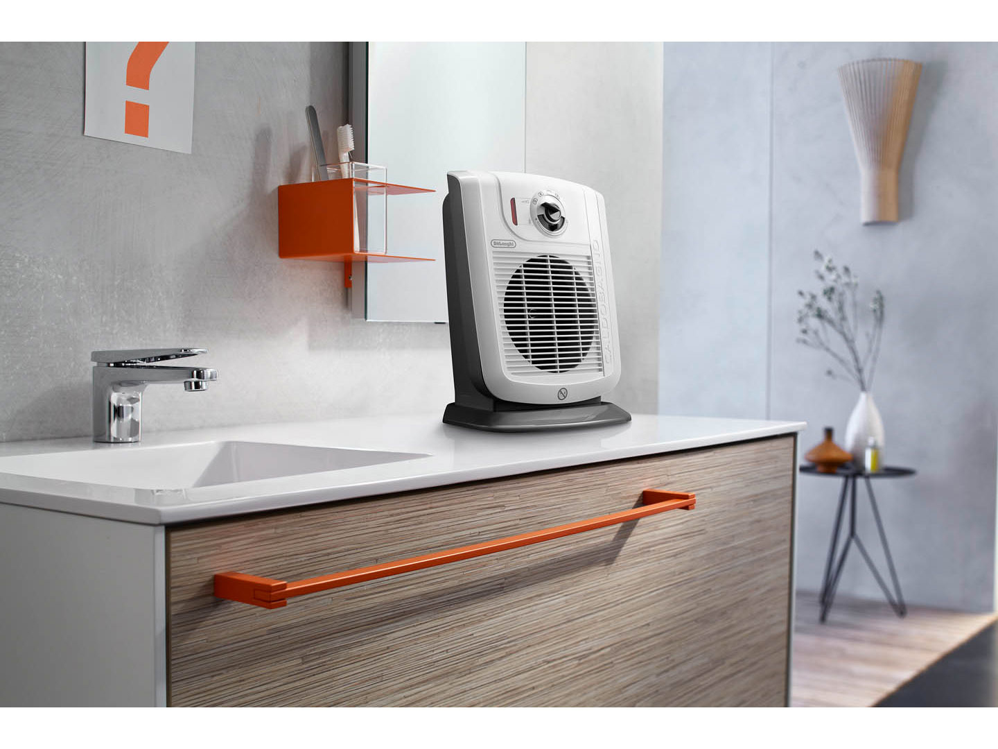 Biały i szary grzejnik wentylatorowy do łazienki na drewnianym blacie ze srebrnym wieszakiem na ręczniki.