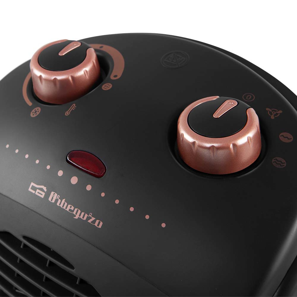 Czarny grzejnik z różowo-złotymi elementami sterującymi. Ma dwa pokrętła i czerwone światło.