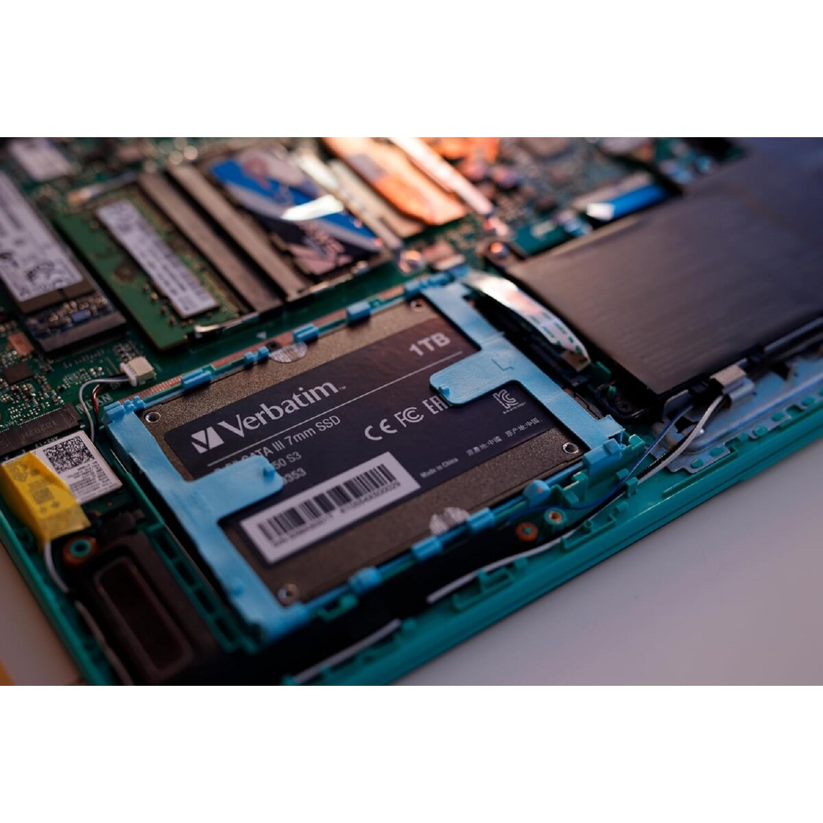 À l'intérieur d'un ordinateur portable, révélant un SSD Verbatim 1 To sur une carte de circuit imprimé verte.