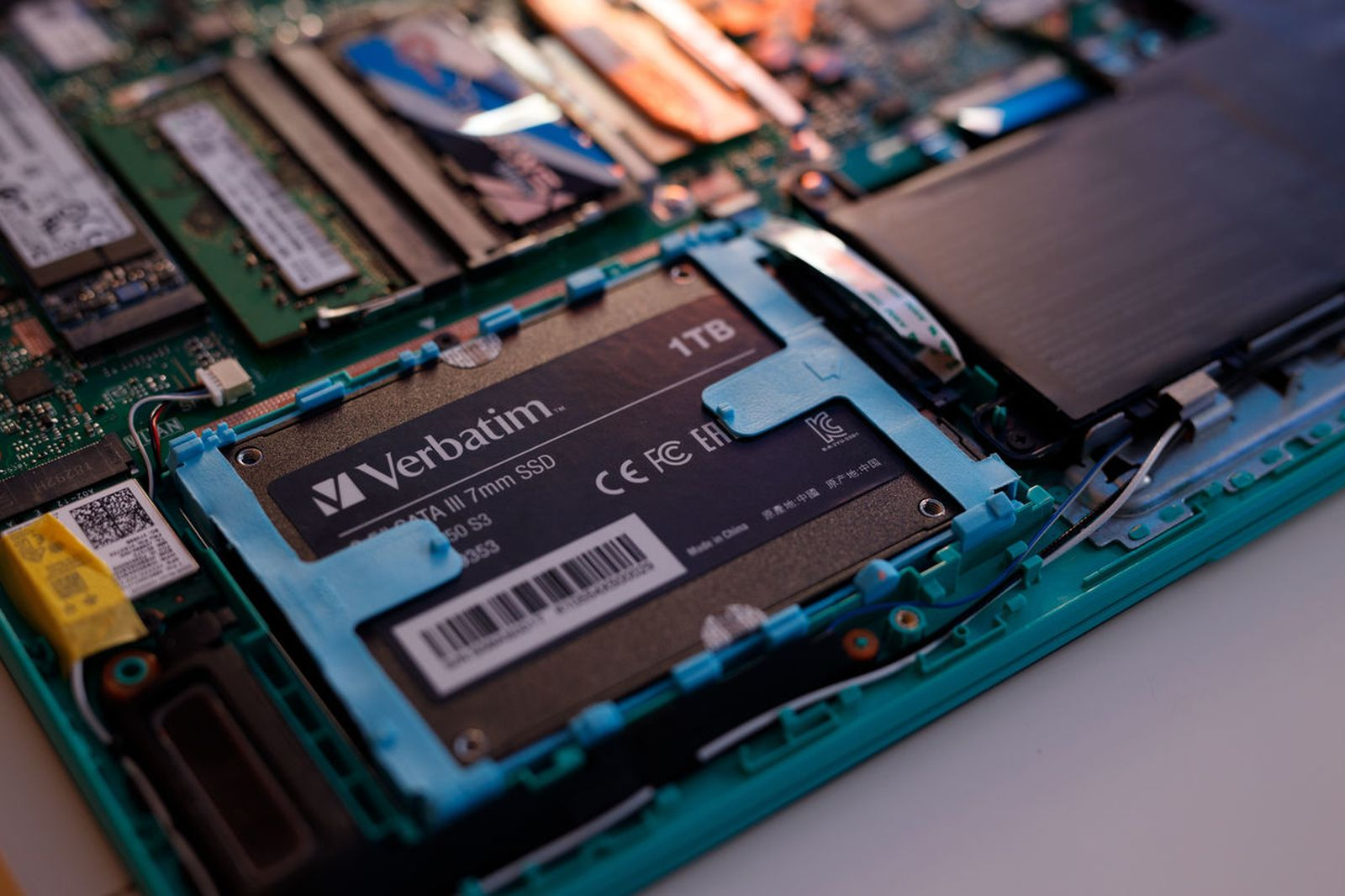 Intérieur d'ordinateur portable avec un SSD Verbatim installé, entouré de circuits imprimés et composants.