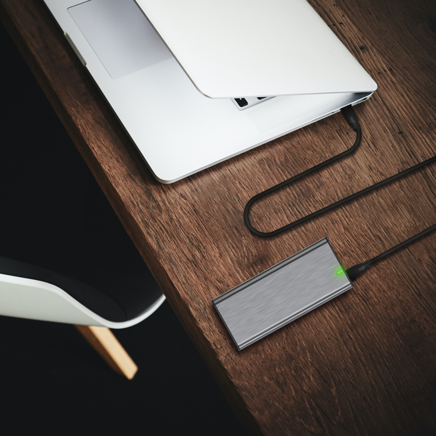 Laptop, externe Festplatte und Kabel auf einem Holztisch. Grünes Licht an.