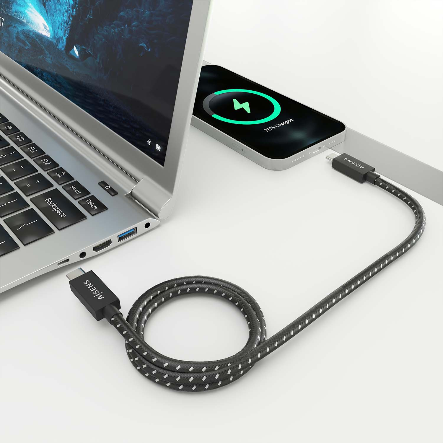 Laptop en telefoon opladen met een zwarte kabel. 75% opgeladen op het scherm. Wit oppervlak.