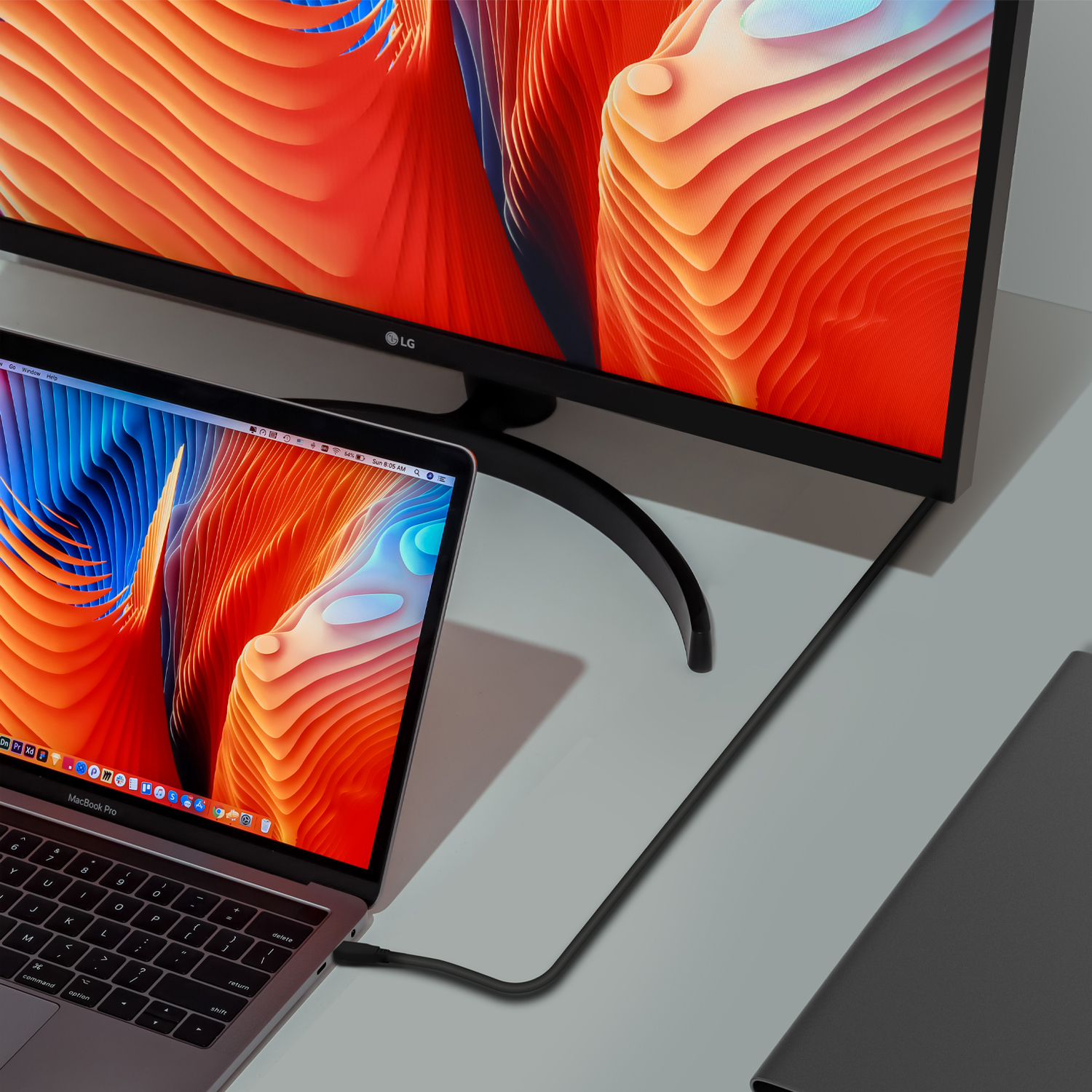 Laptop und Monitor verbunden. Der Monitor zeigt ein abstraktes Design. Der Laptop ist geöffnet.
