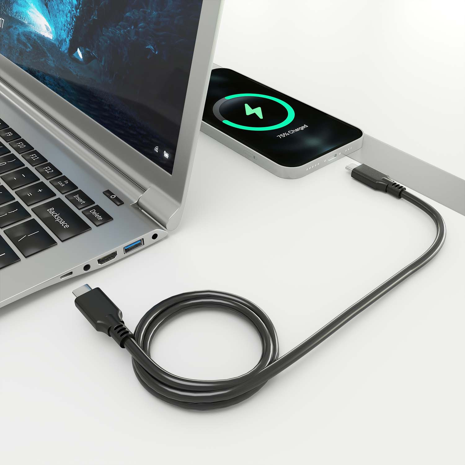 Laptop en telefoon opladen met een zwarte kabel. Wit oppervlak.