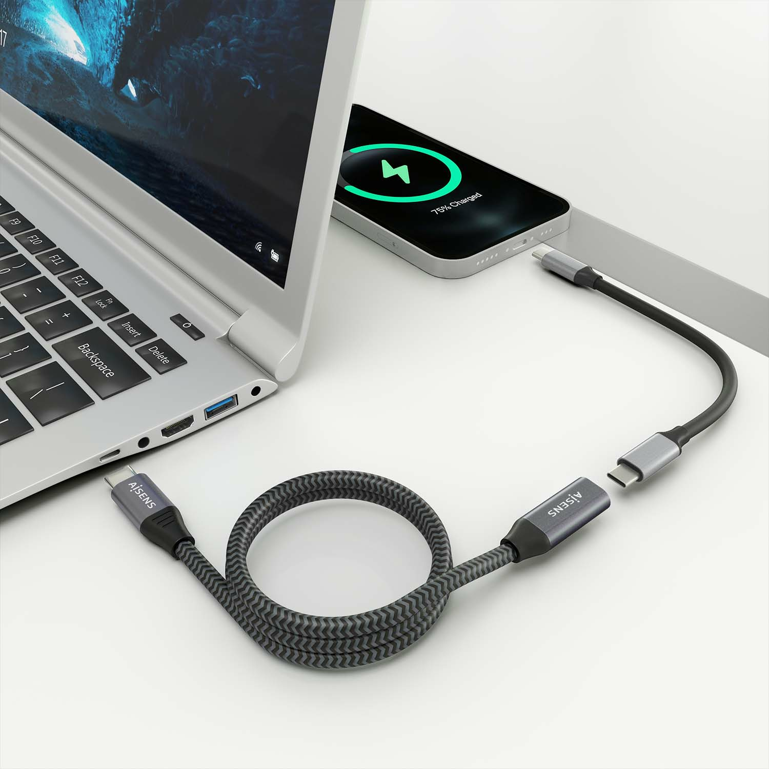 Laptop en telefoon verbonden met een zwart-grijze USB-C-kabel op een wit oppervlak.