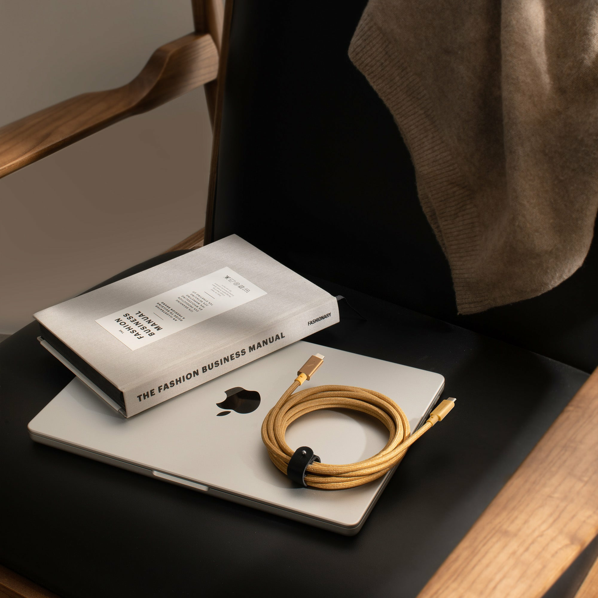 Laptop, libro e cavo su una sedia. Un maglione è appoggiato sulla sedia.