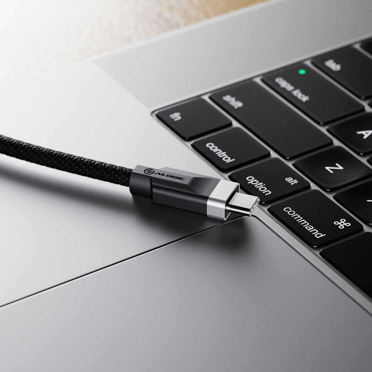 Un cavo USB-C nero collegato a un laptop. Il cavo è sulla superficie. Sfondo nero.