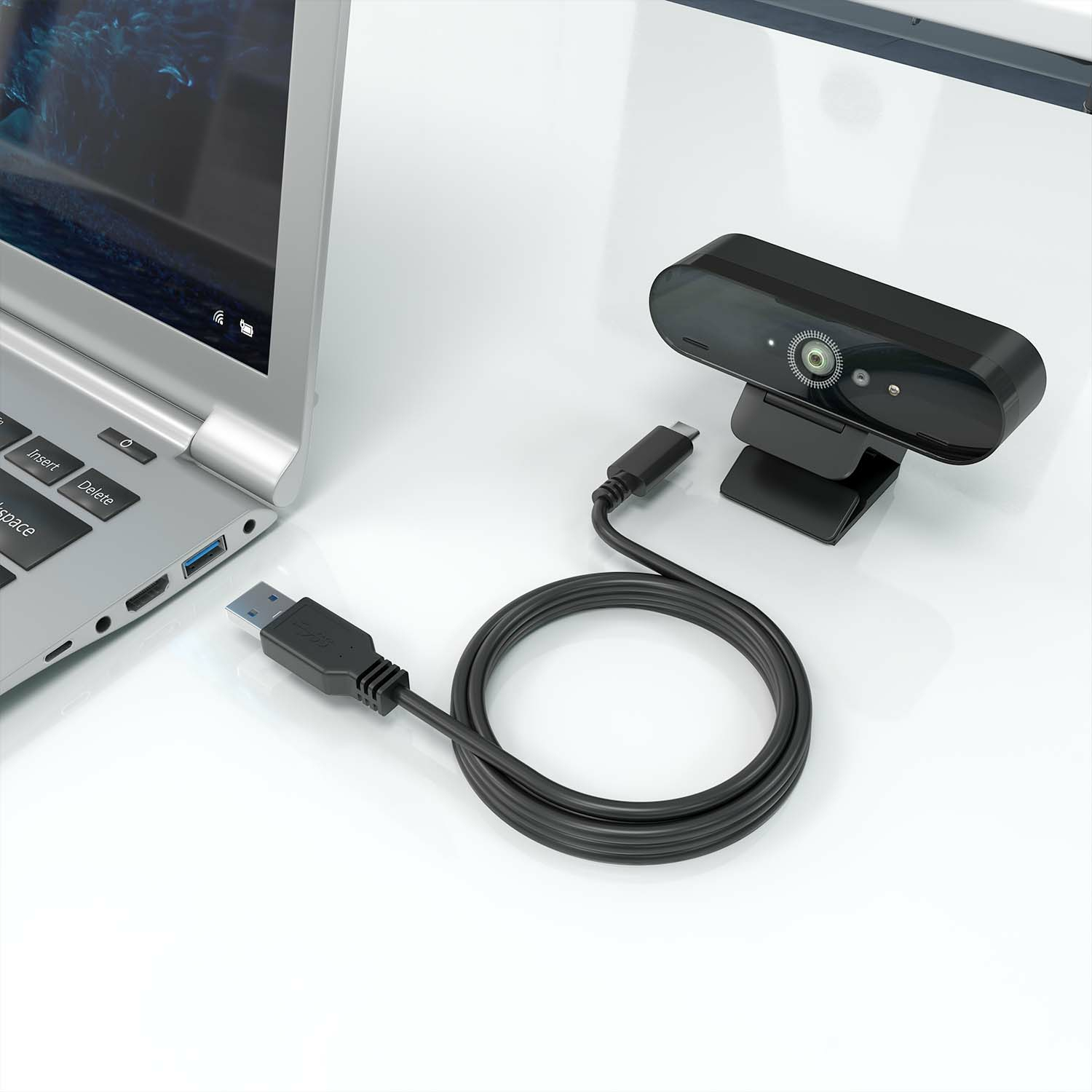 Webcam connected to a laptop with a USB cable on a white surface.